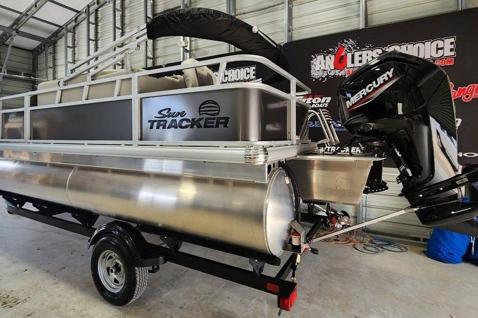 2026 Sun Tracker Bass Buggy 18 DLX pontoon boat with Mercury engine in showroom.