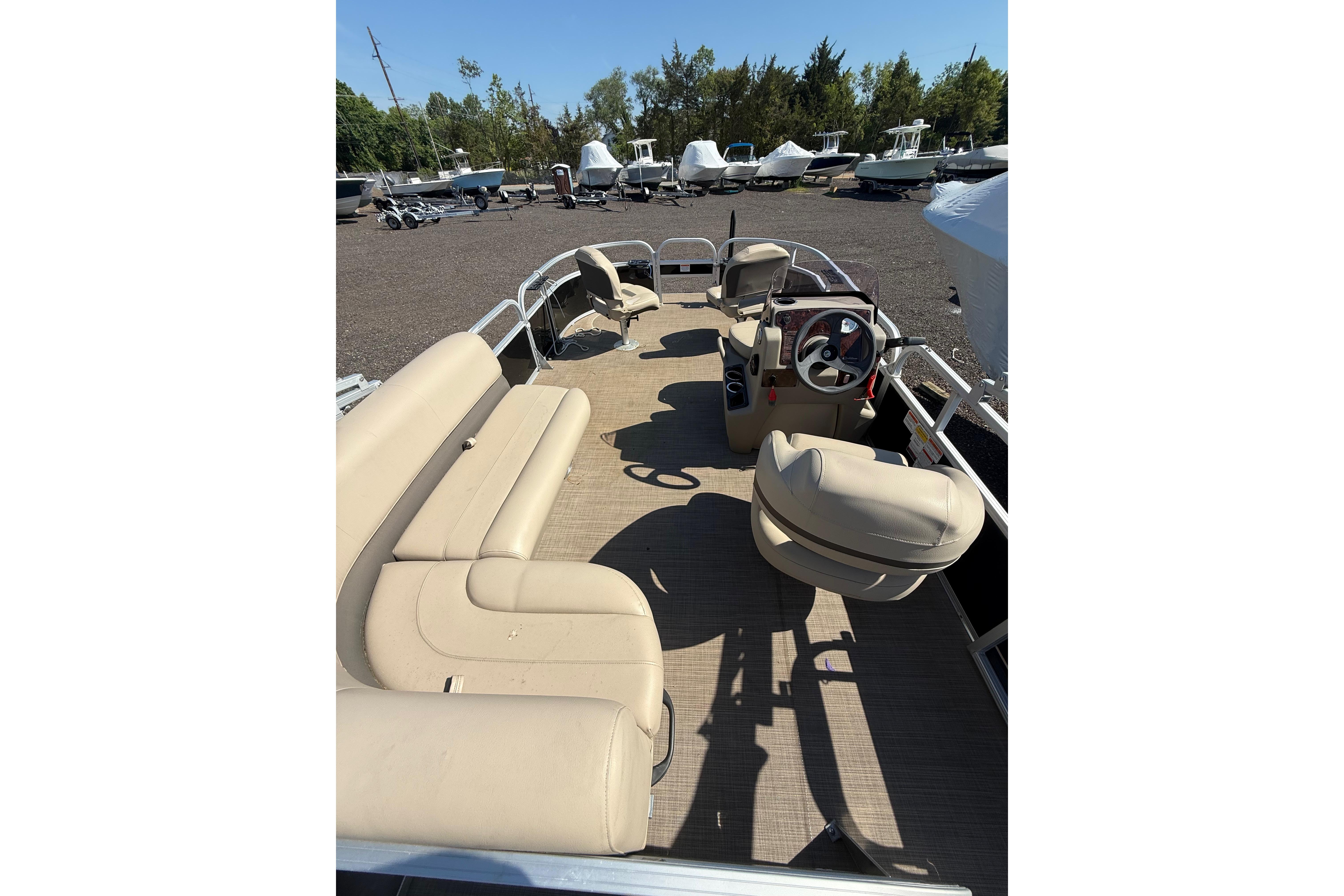 2021 Sun Tracker Bass Buggy 16 XL Select pontoon boat with beige seating and steering console.