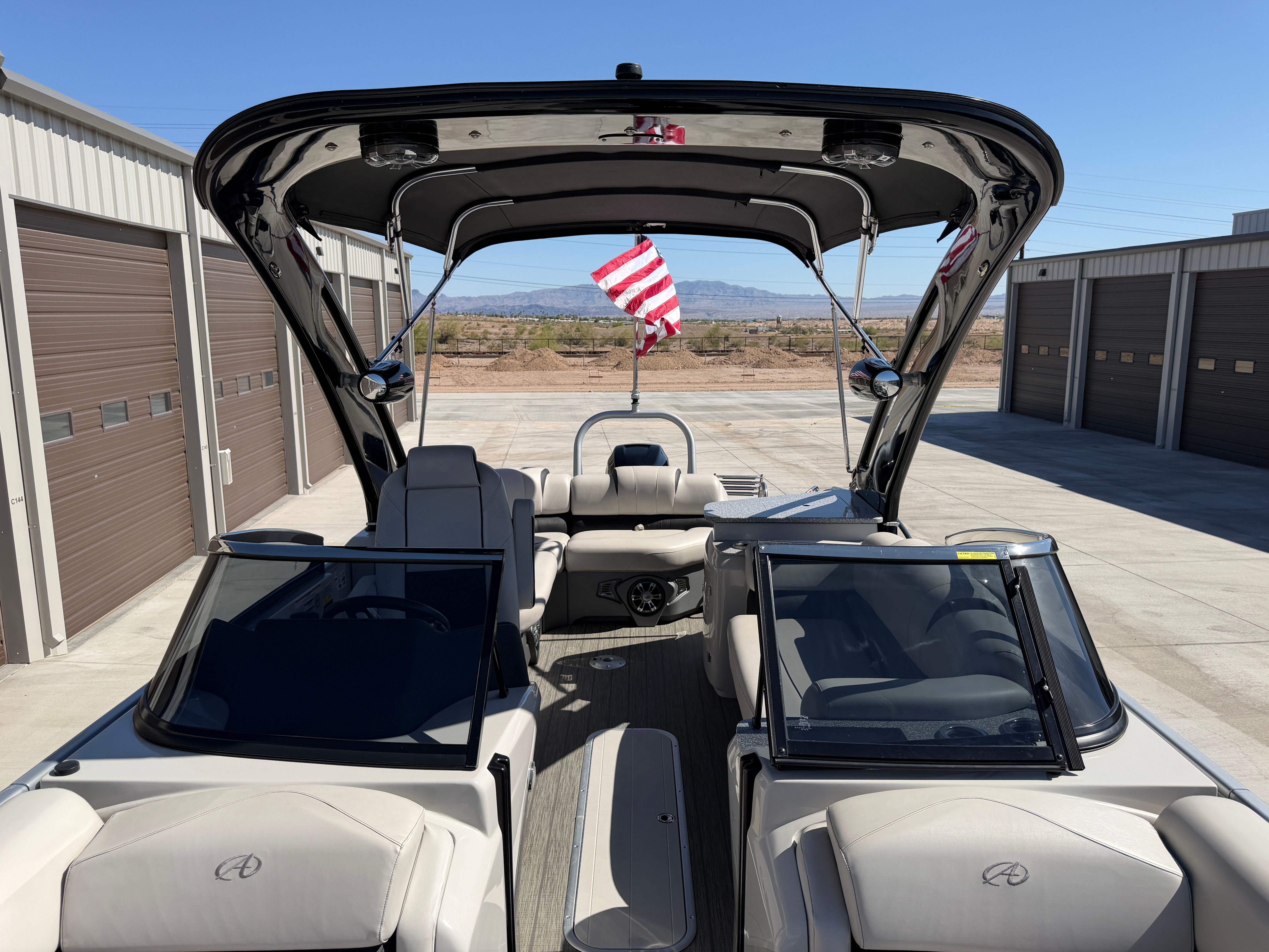 A 2021 Avalon 2785 boat with open deck and American flag, parked in a storage area.