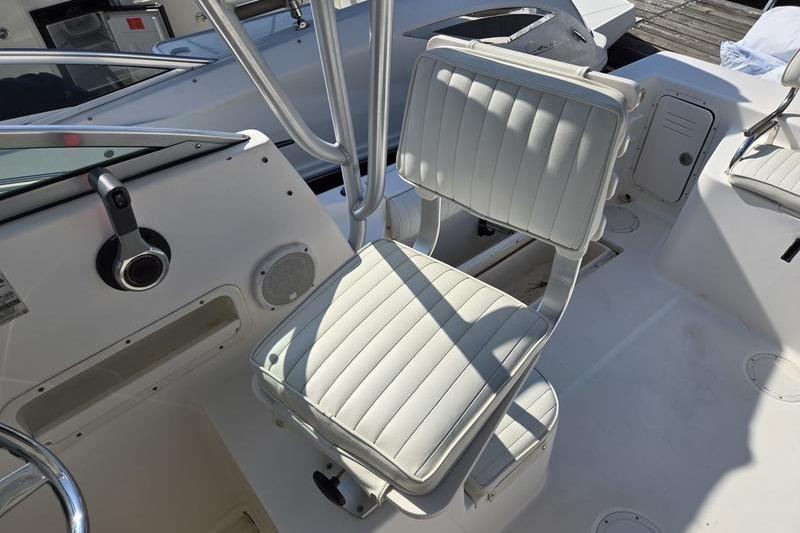 2004 Robalo R235 Walkaround boat interior with white cushioned seating and steering area.