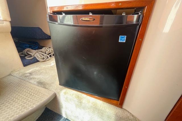 Compact fridge inside 2003 Sea Ray 260 Sundancer boat cabin, with ropes nearby.