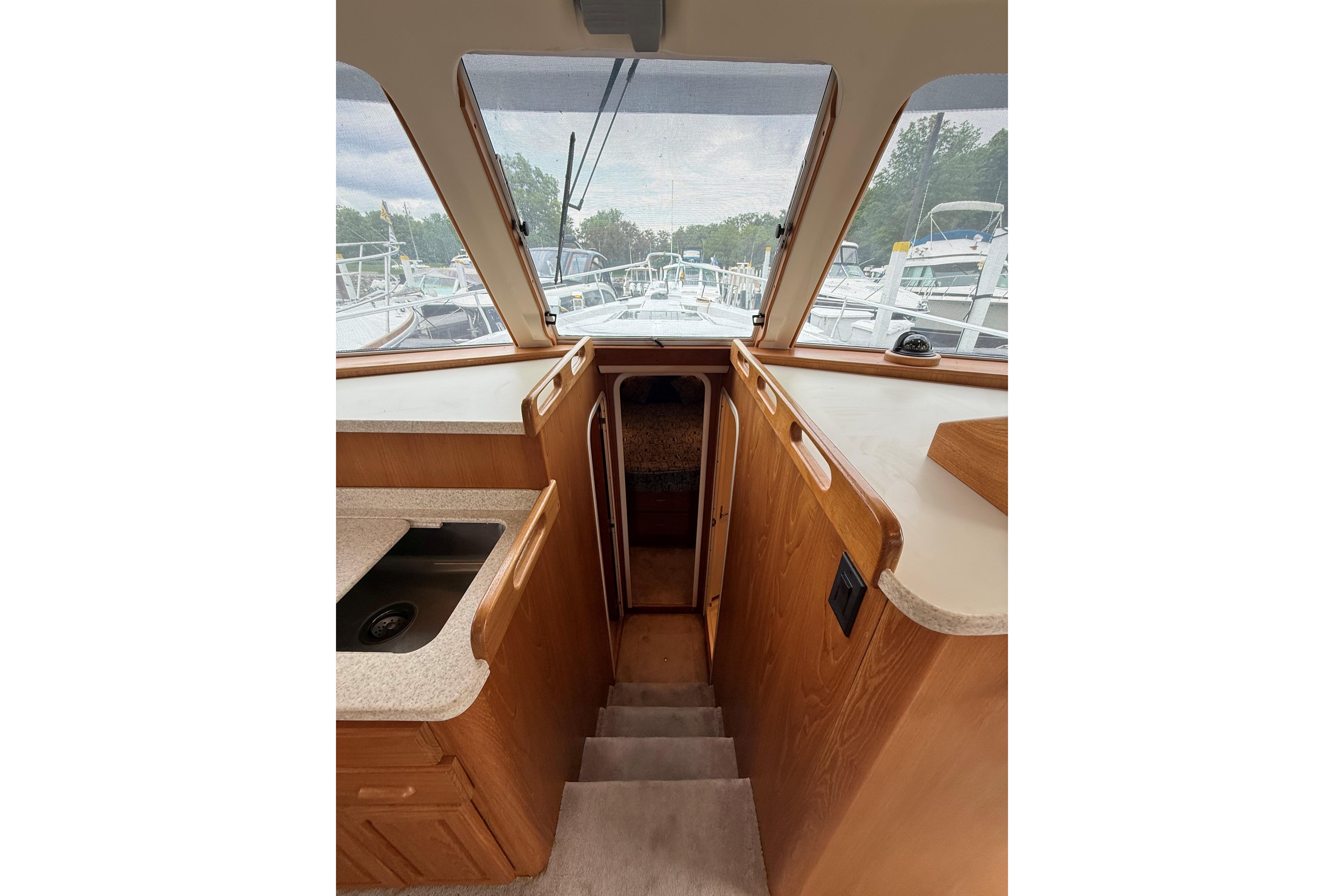 Interior view of 1999 Mainship 350 Trawler, featuring wooden cabinetry and steps.