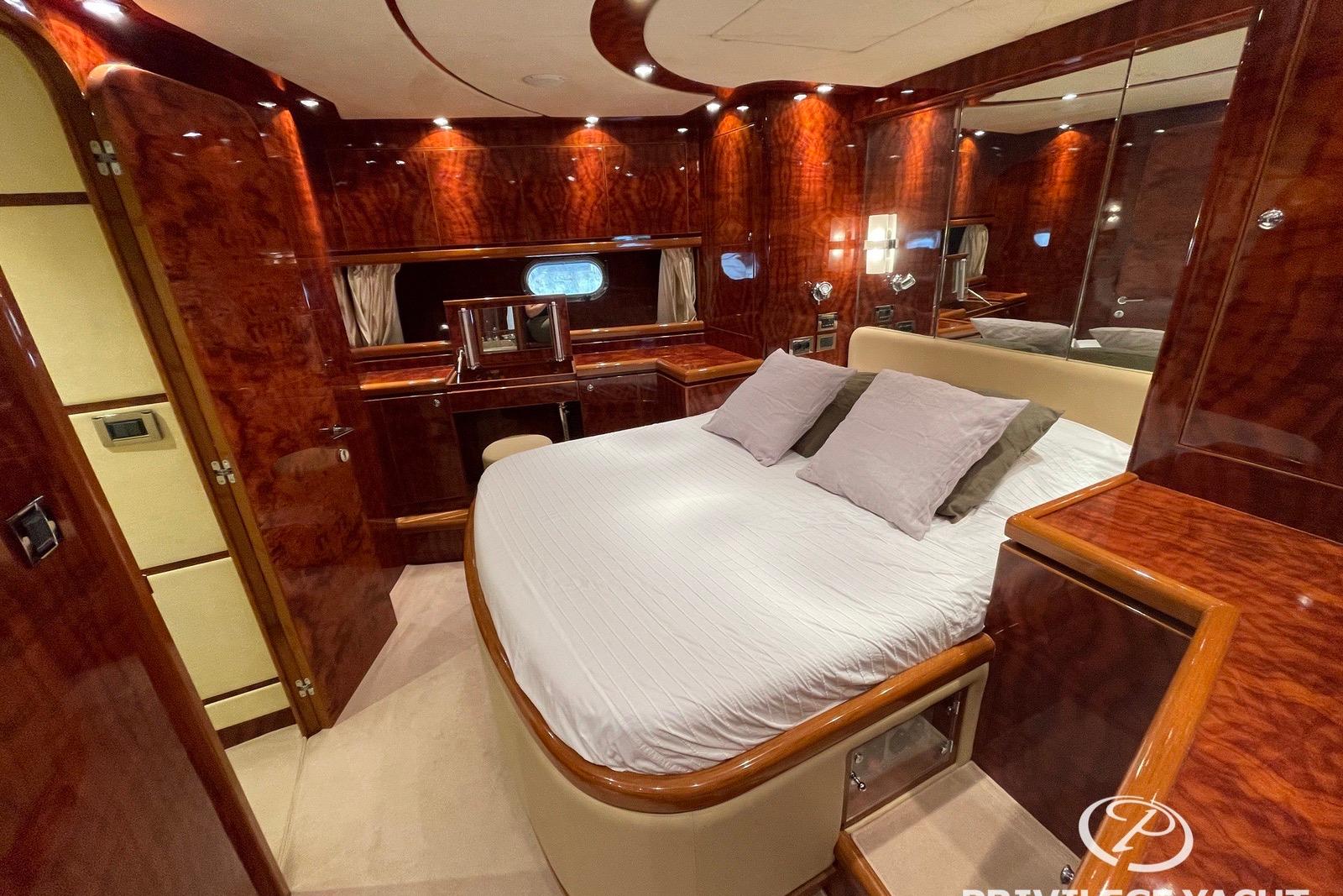 Luxurious 2006 Monte Fino 76 yacht bedroom with elegant wood finish and plush bedding.