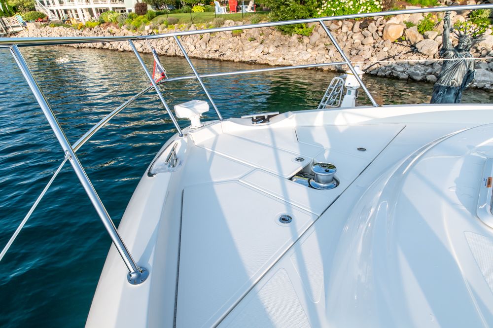 Riviera 6000 Sport Yacht Platinum 2022 on water near rocky shoreline.
