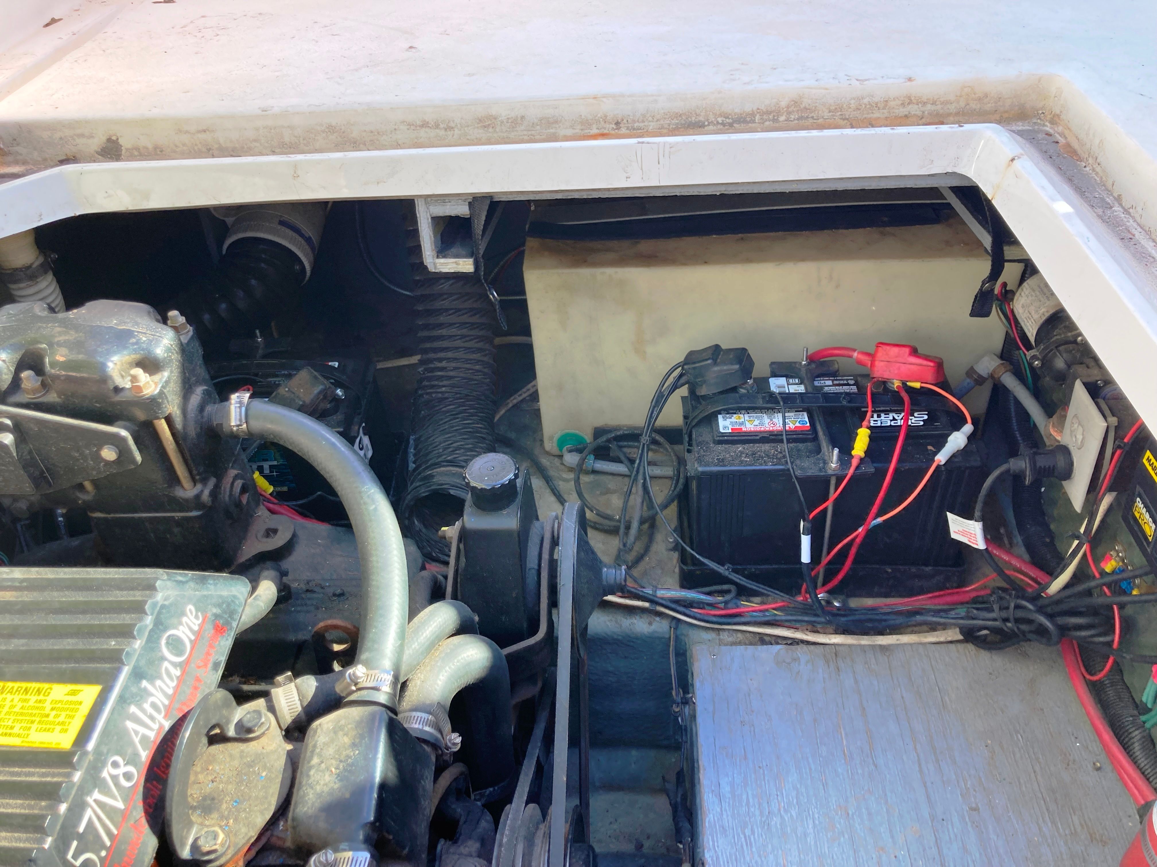 The engine compartment of a 1991 Sea Ray 220 Sundancer shows the engine and battery.