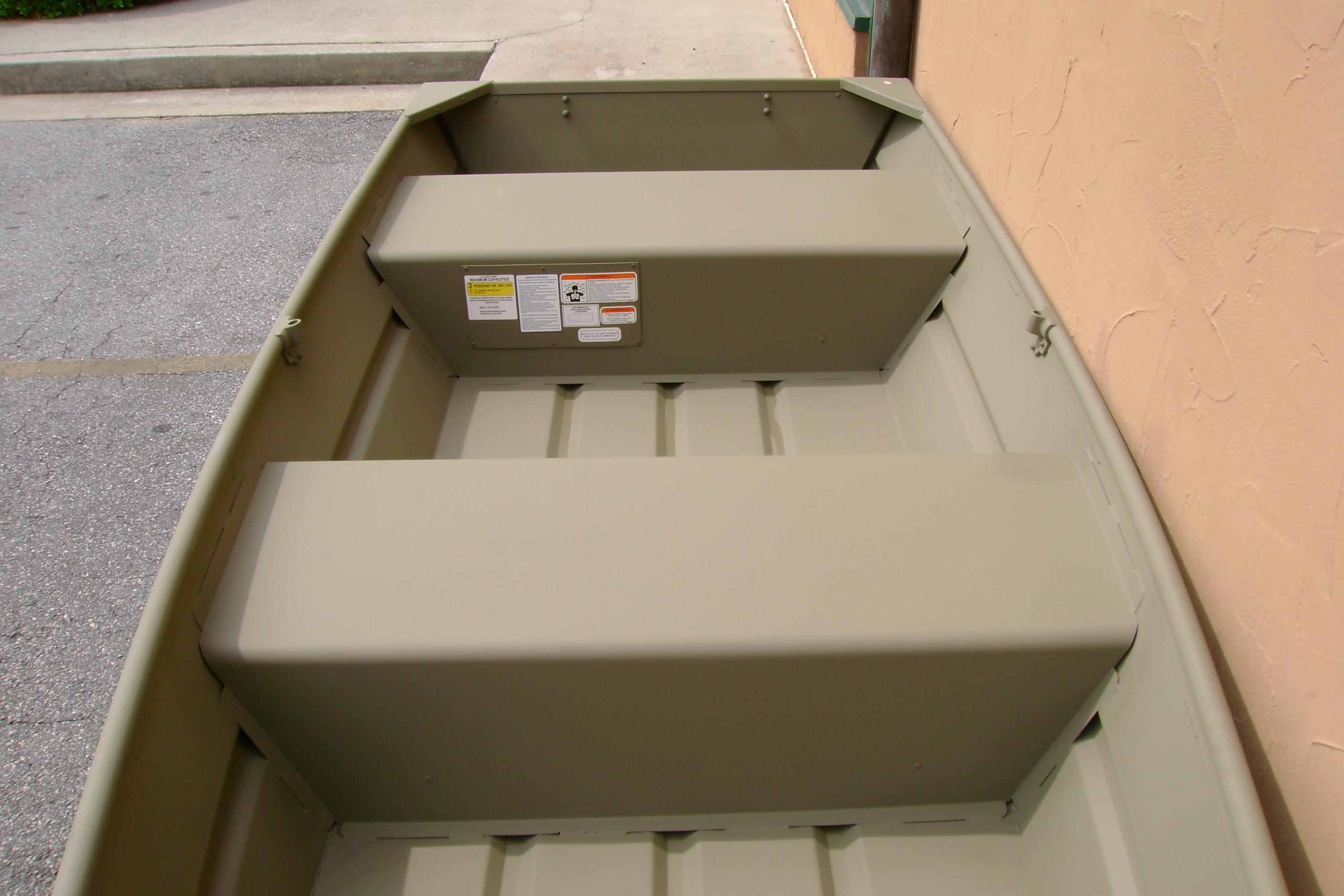 2026 Tracker Grizzly 12 Jon boat interior with bench seats, parked on pavement.