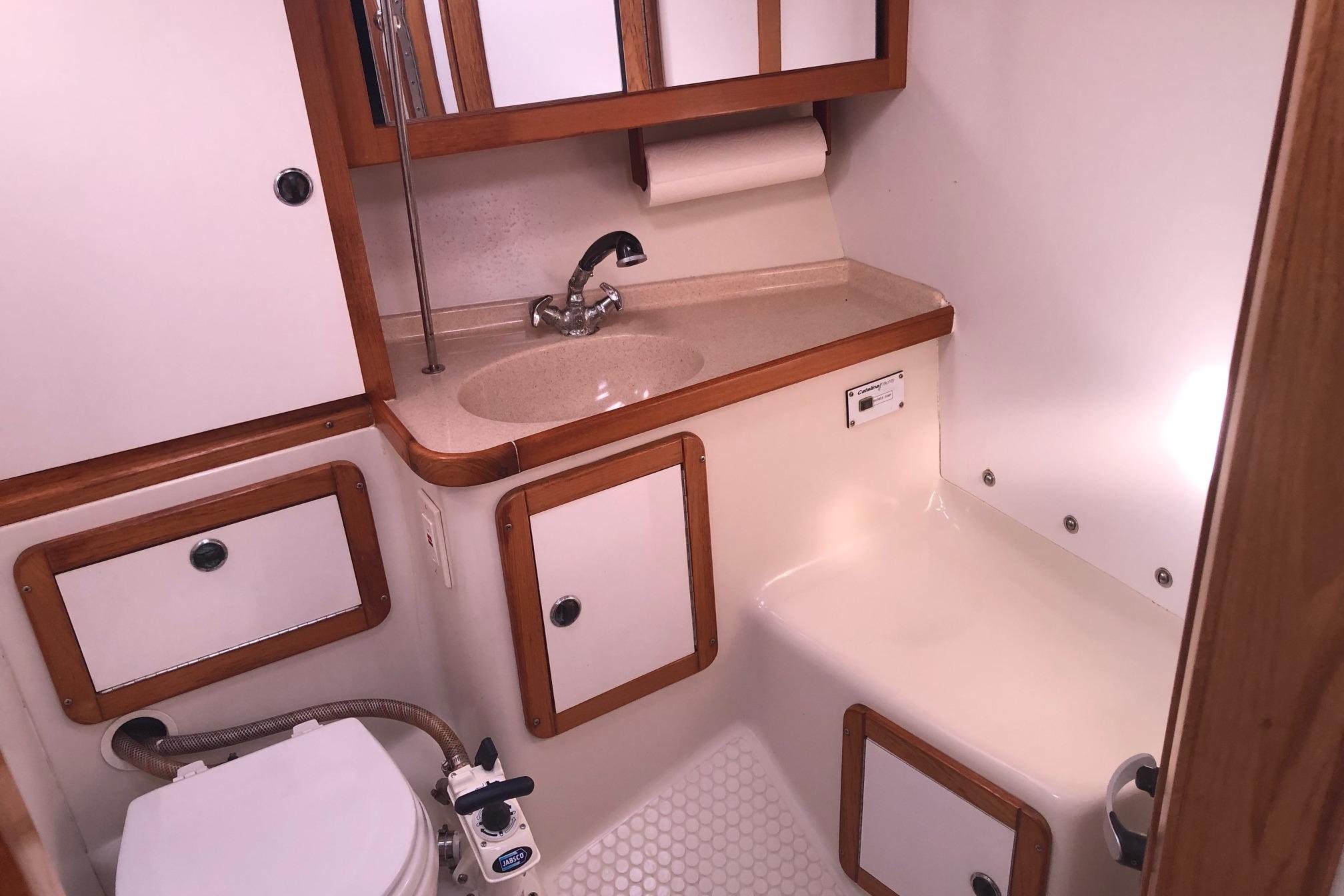 2000 Catalina 36 MkII yacht bathroom with sink, toilet, and wooden cabinetry.