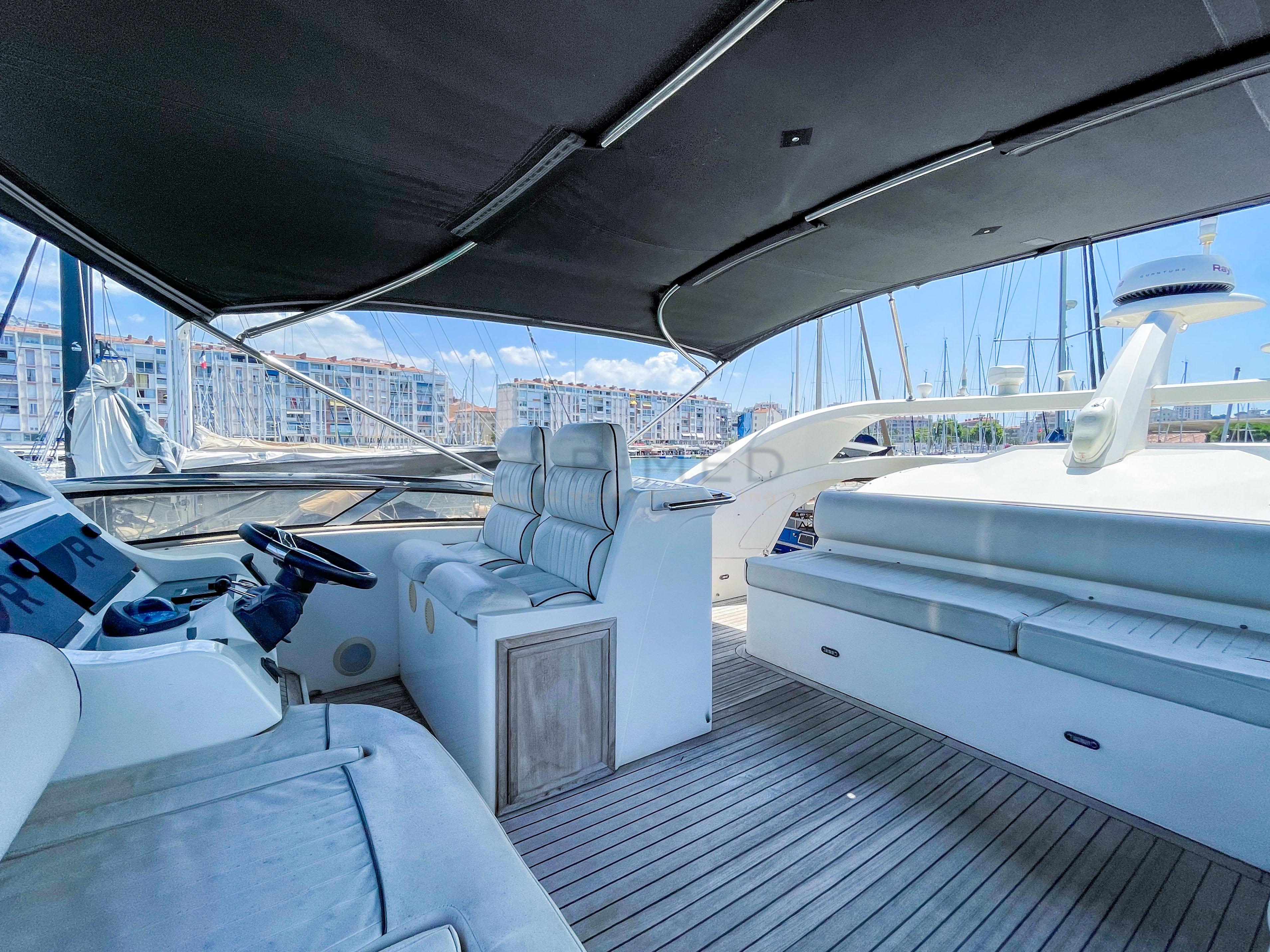 Luxurious 2006 Pearl 60 yacht interior with plush seating and modern helm, docked in marina.