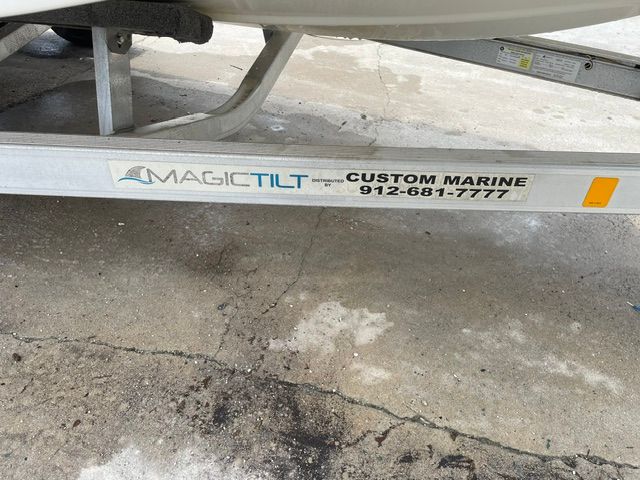 A boat trailer labeled "Magic Tilt" and "Custom Marine" on a concrete floor.