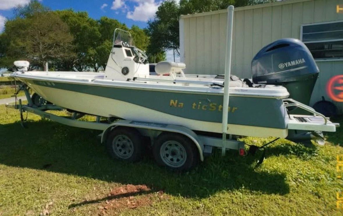 A 2022 Custom 215 XTS boat on a trailer beside a building.