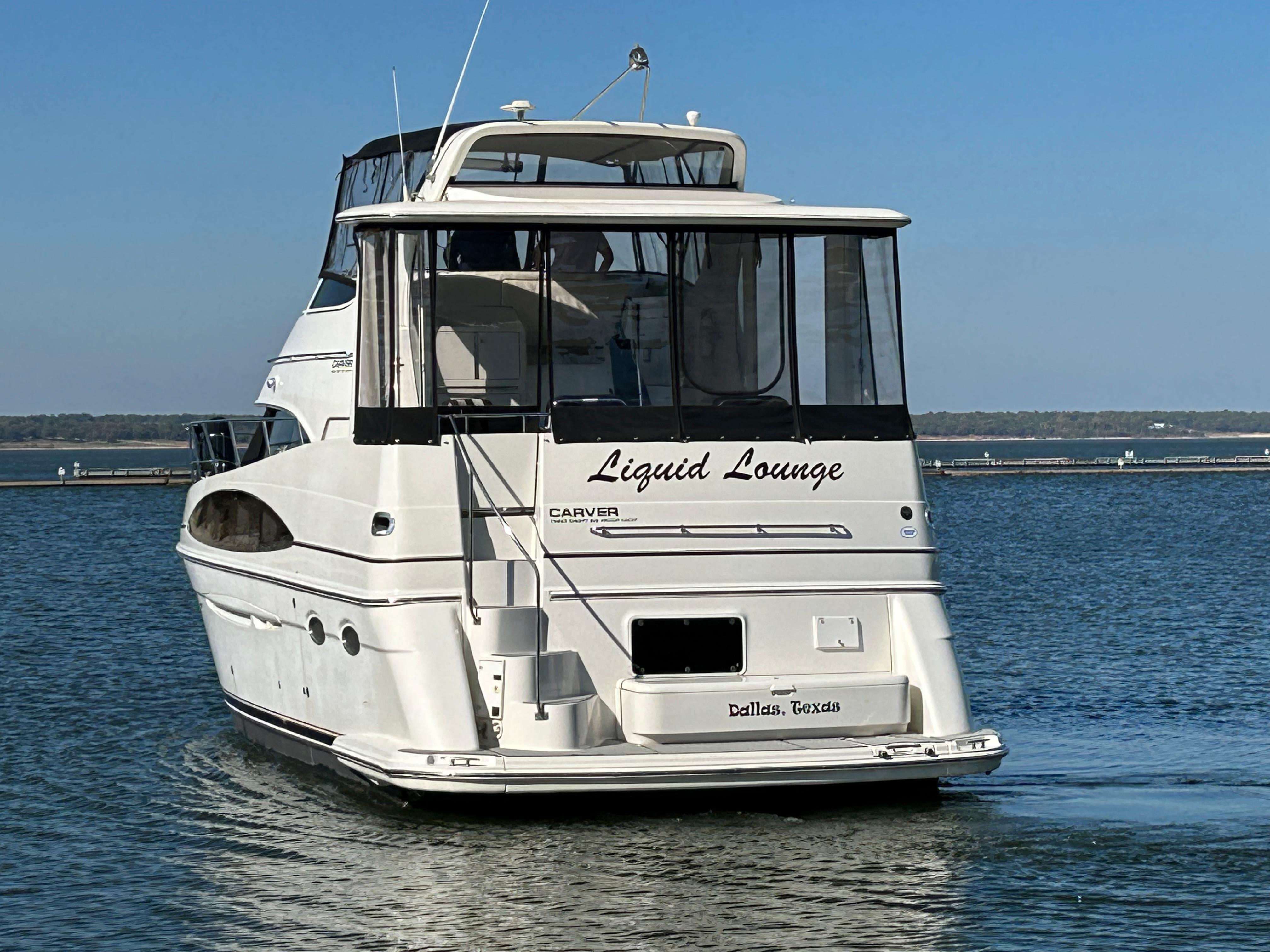 2000 Carver 396 yacht named "Liquid Lounge" on calm water, rear view.