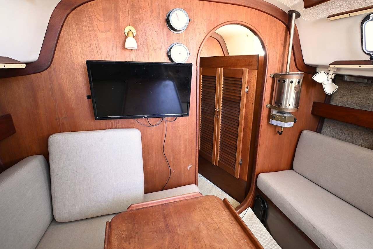 Interior of 1977 Mercator Offshore boat with wood paneling, seating, and a mounted TV.