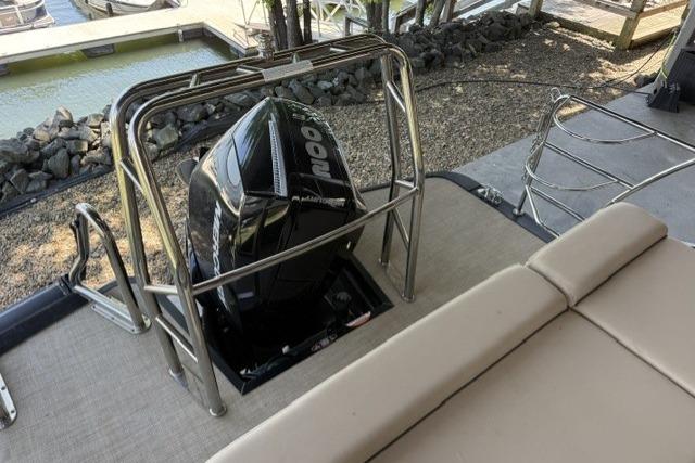 2025 Harris Sunliner 230 boat with powerful outboard motor, docked near a serene waterfront.