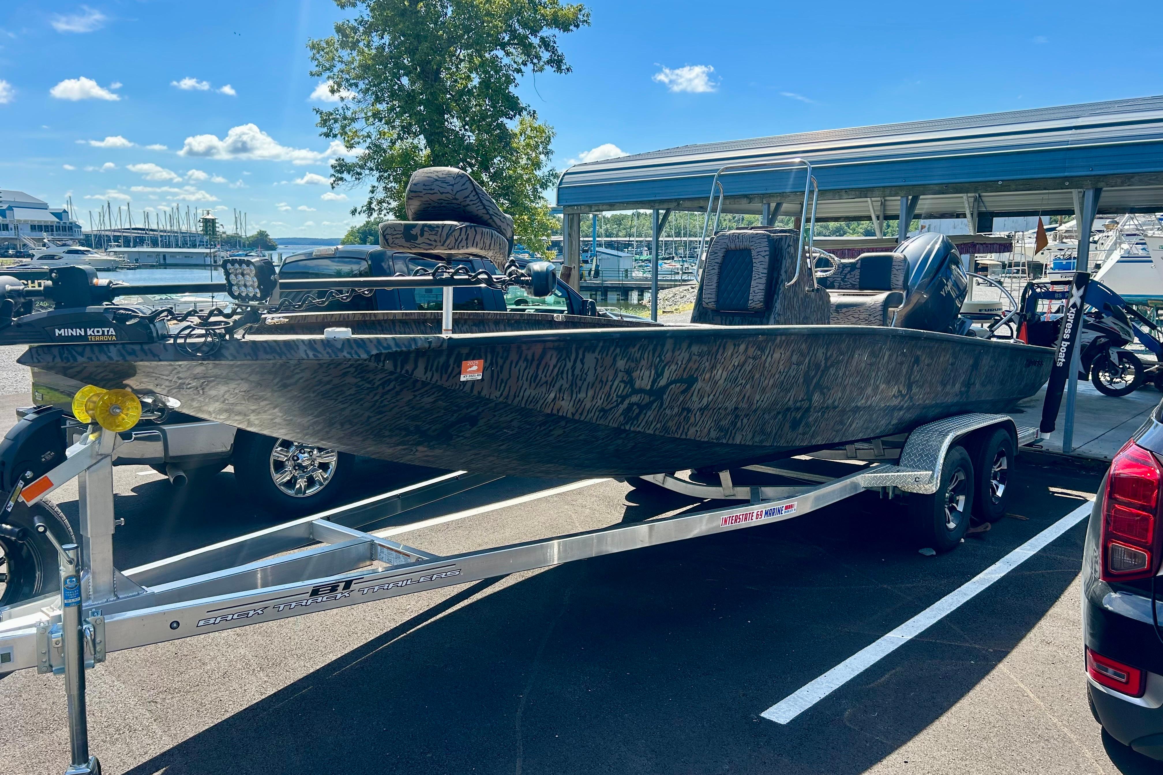 2025 Xpress H22B Bay boat on trailer at marina, sunny day.