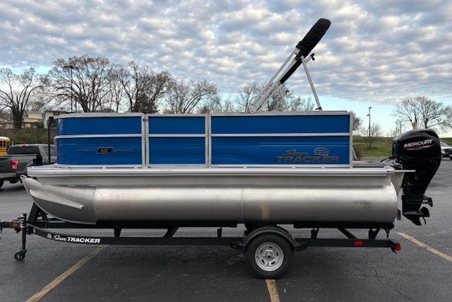 2026 Sun Tracker Party Barge 16 DLX pontoon boat on trailer, parked outdoors.