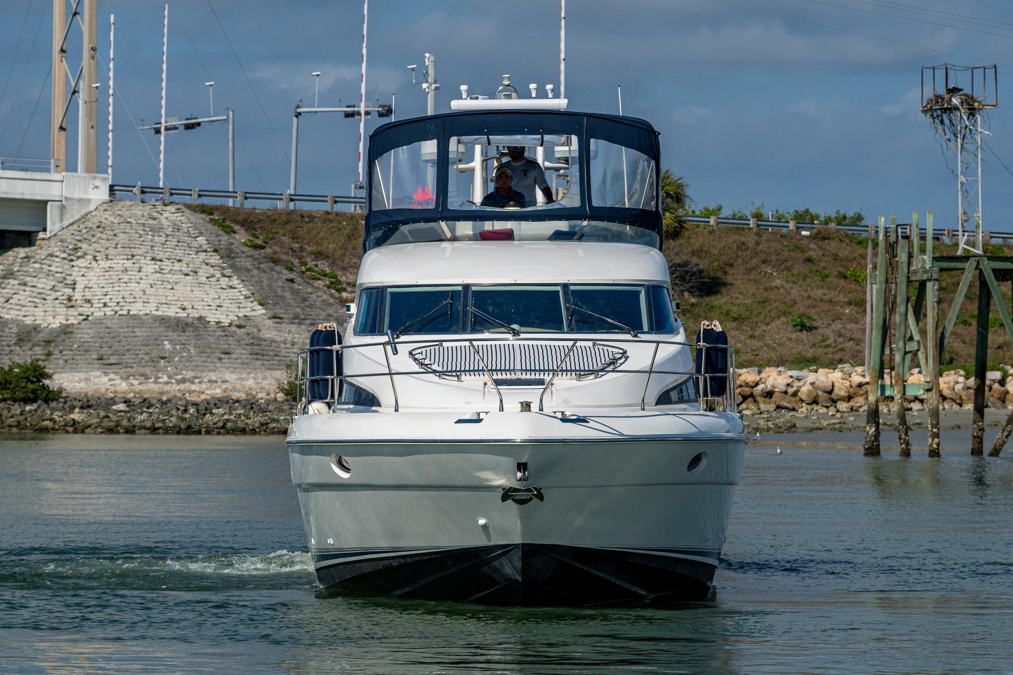 Front view of a 2000 Fairline Squadron 52 yacht navigating a calm waterway.