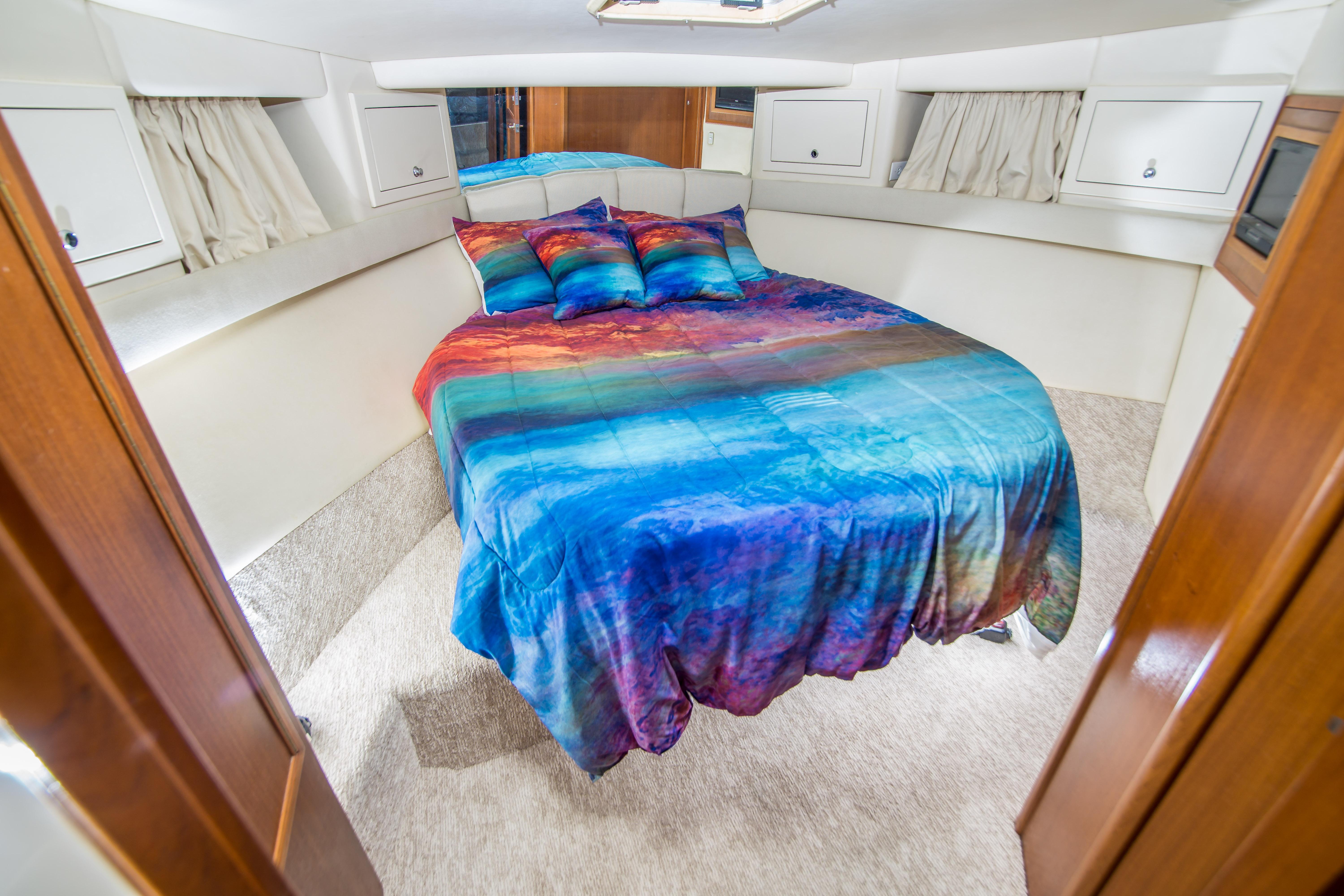 Luxurious bedroom in 1999 Riviera 43 Open Flybridge yacht with vibrant bedding.