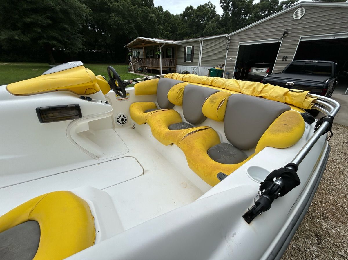 A 2004 Sea-Doo Sportster LE DI with yellow and gray seats, parked in front of a garage.