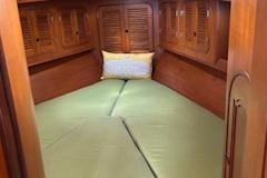 Cozy cabin interior of a 1995 Mason 33 sailboat with wooden paneling and green bedding.
