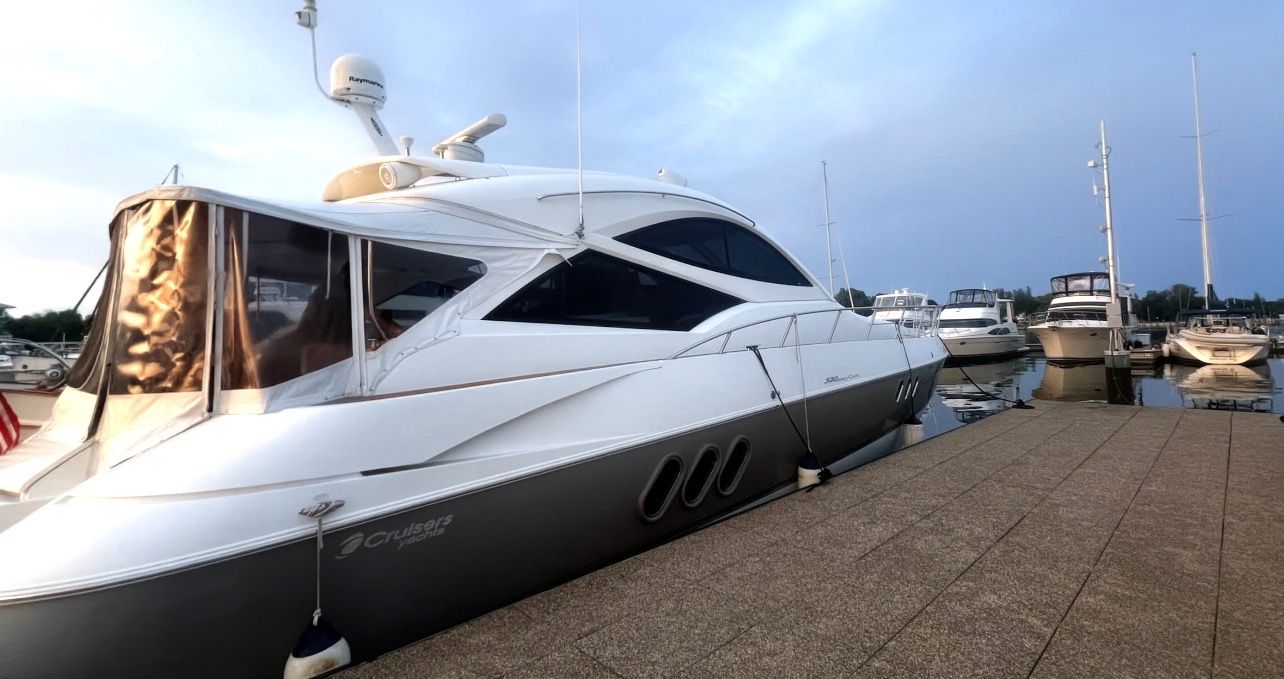 A 2009 Cruisers Yachts 520 Sports Coupe docked. Sleek design with an enclosed cabin.
