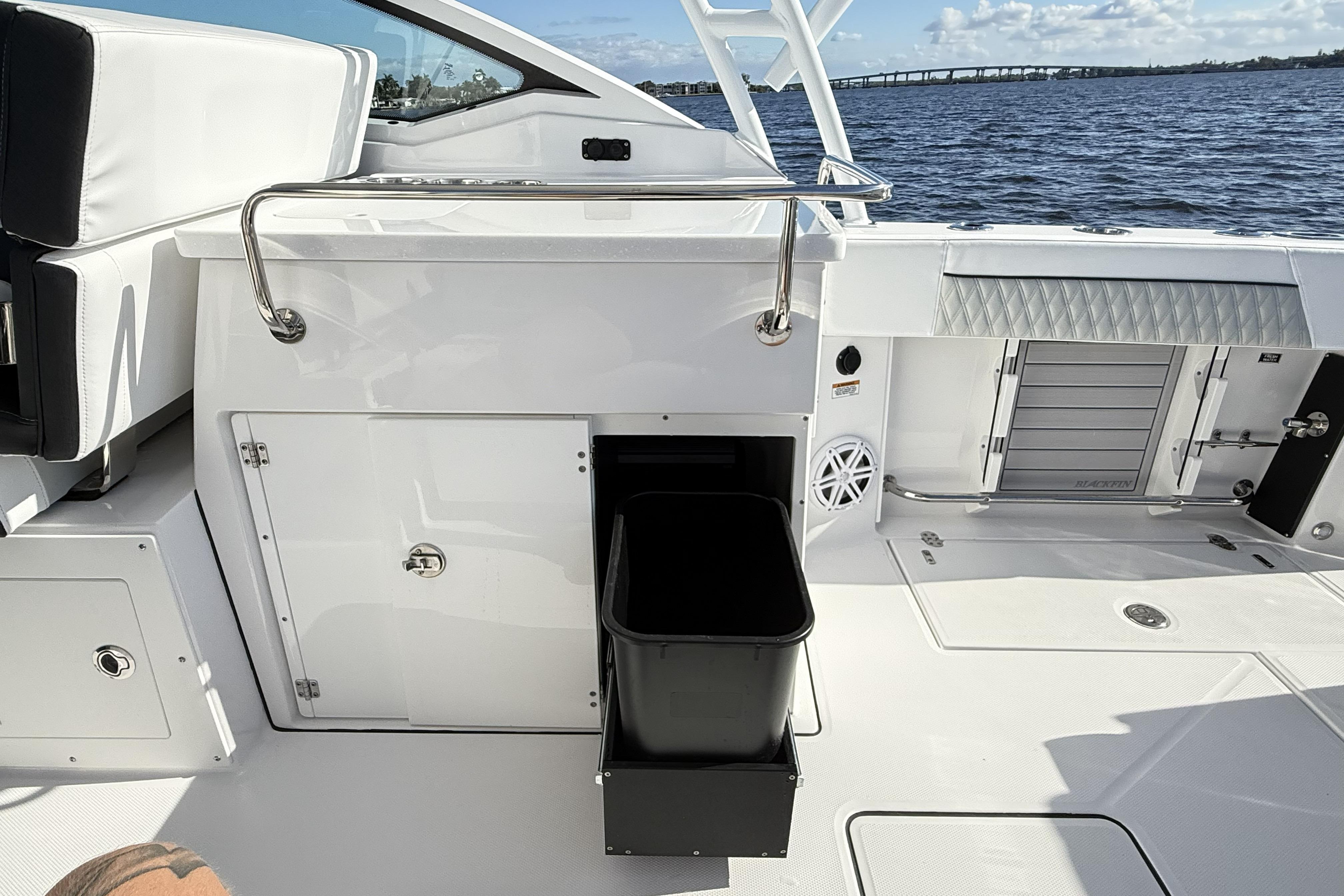 2025 Blackfin 272 DC boat interior with storage compartments and seating, overlooking water.