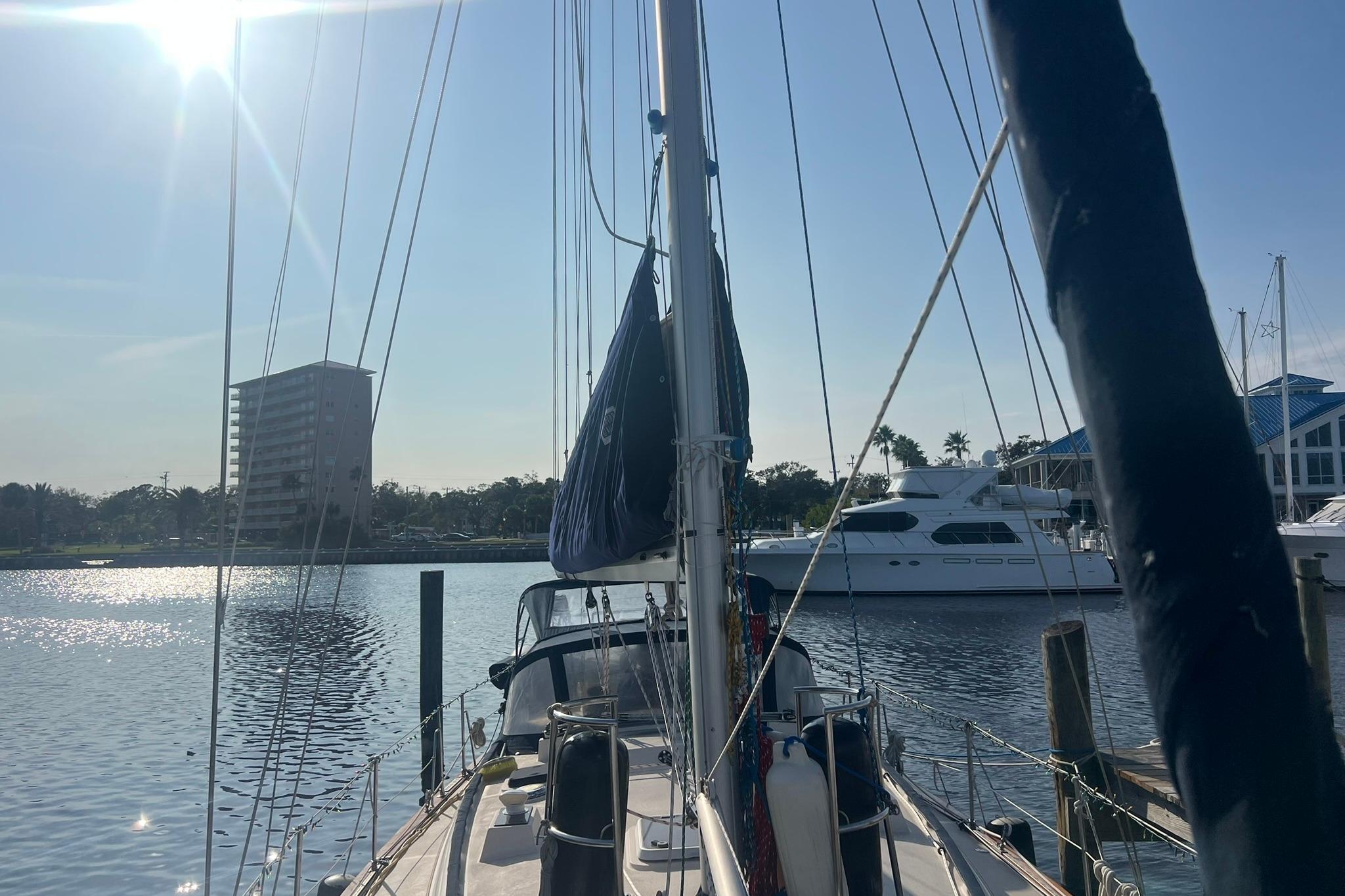 1994 Island Packet 44 cutter sailboat docked in sunny marina with buildings in background.