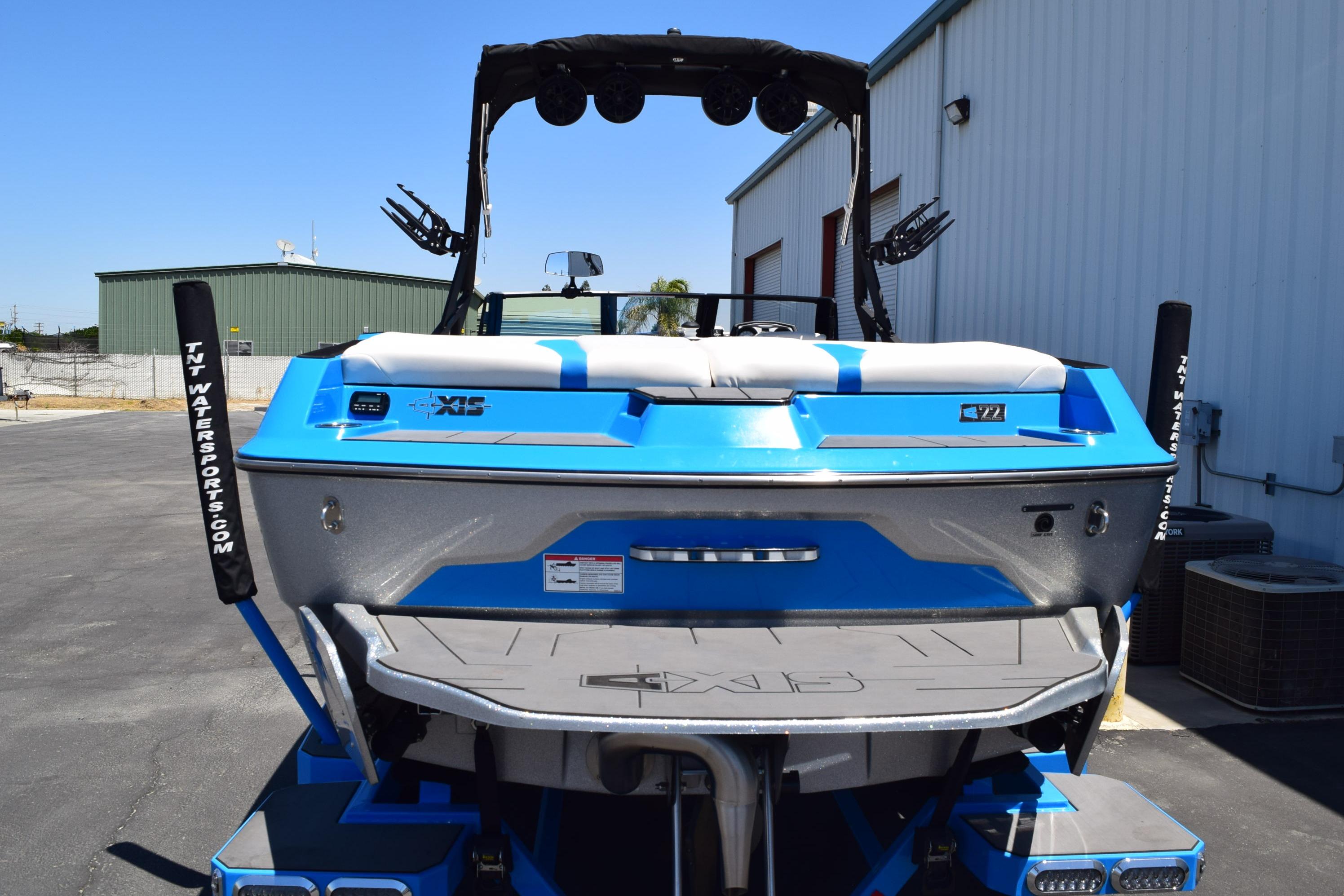2019 Axis A22 boat in blue, parked outdoors near industrial buildings.