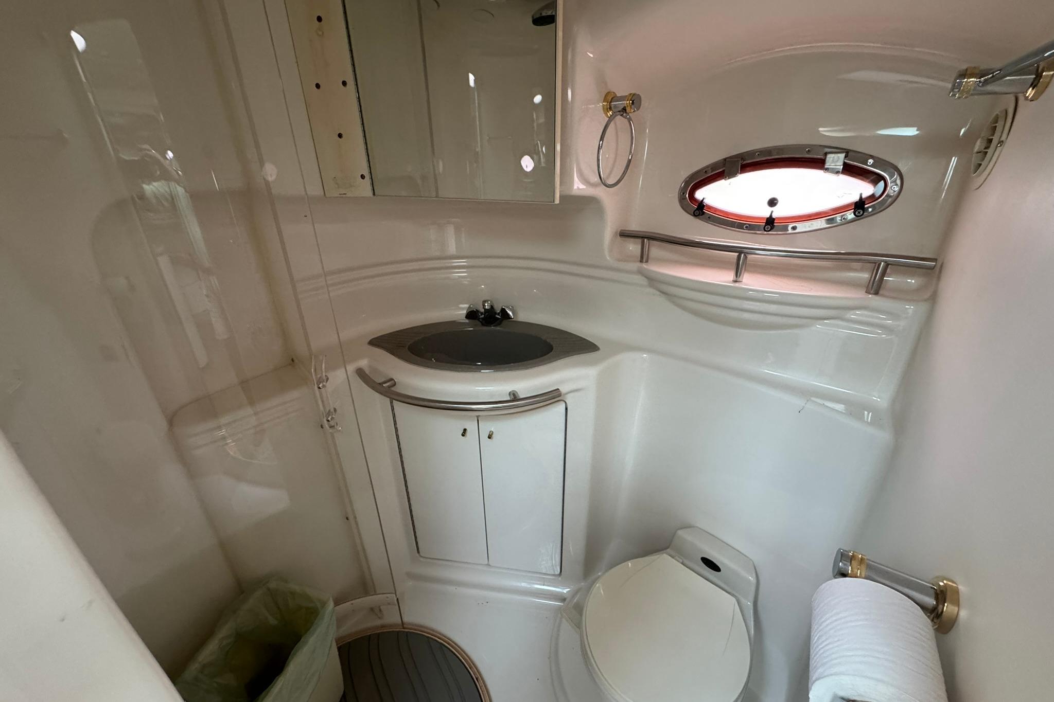1998 Maxum 3700 SCR yacht bathroom with sink, toilet, and porthole window.
