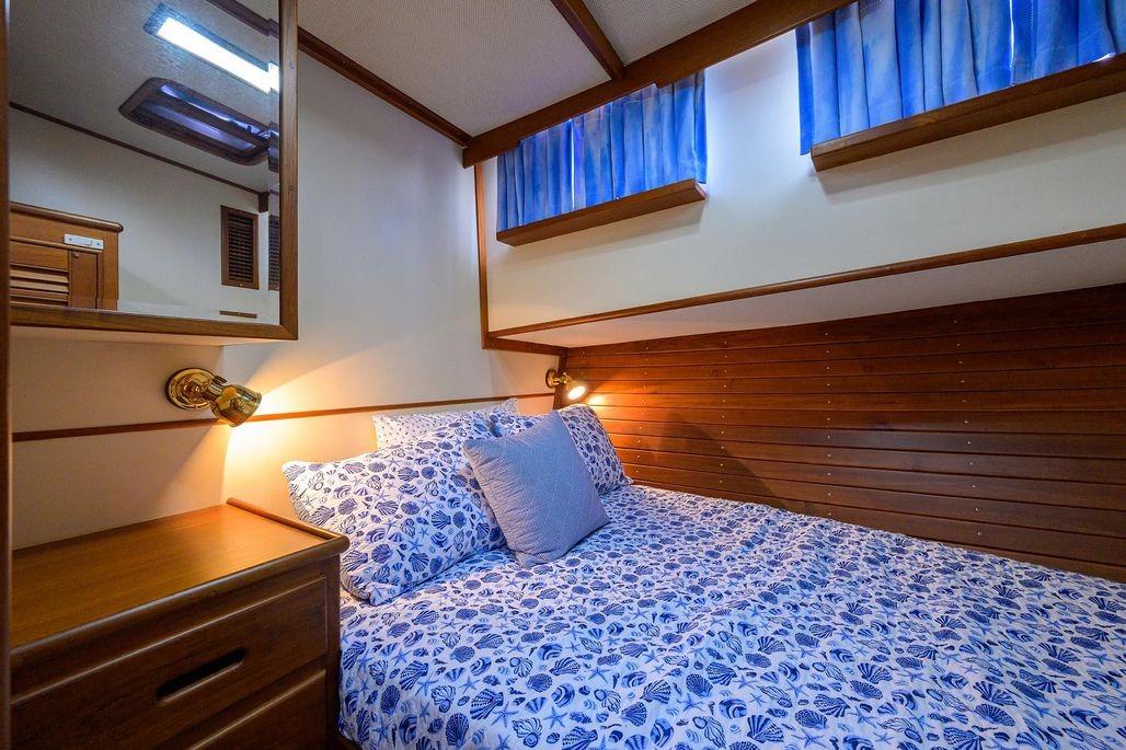 Cozy cabin interior of 1999 Grand Banks 42 Europa with blue floral bedding and wooden accents.