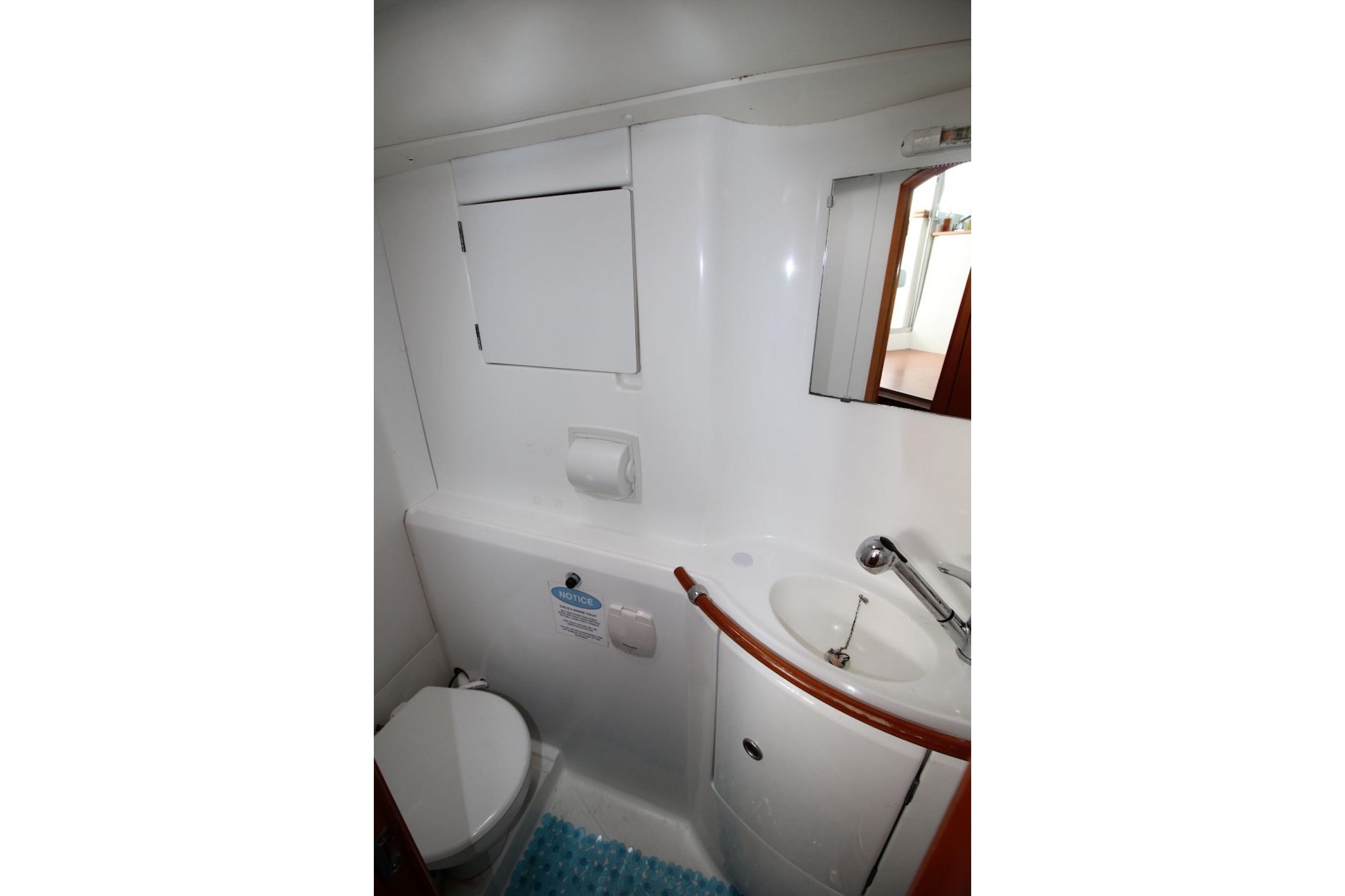 Bathroom interior of a 2004 Lagoon 380 catamaran, featuring a compact sink and toilet.
