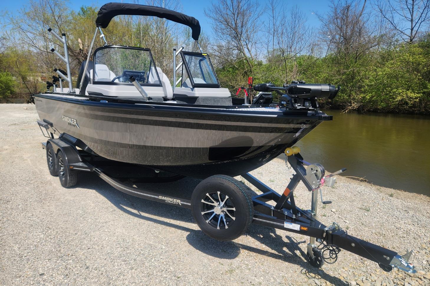 2026 Smoker Craft Adventurer 210 GLS Sport boat on trailer by a riverbank.