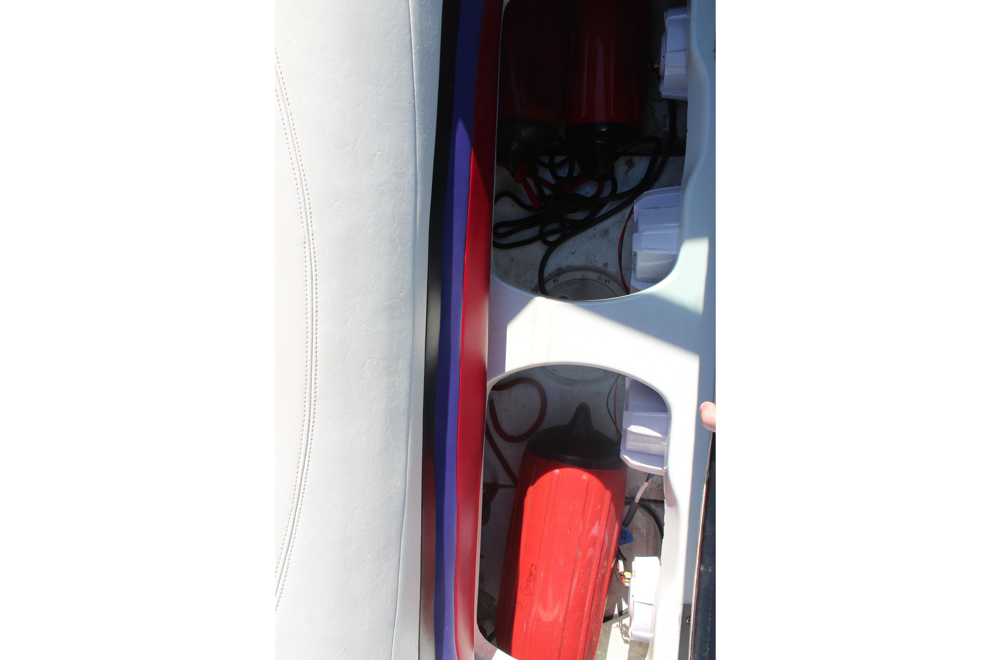 Interior view of a 1996 Baja 232 boat showing storage compartments and equipment.