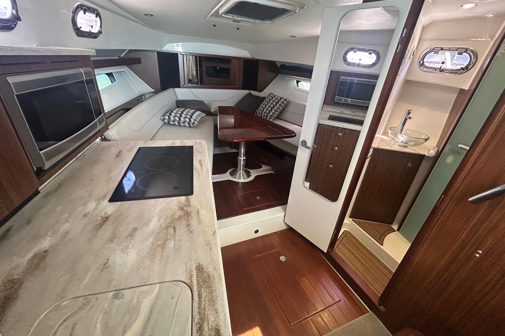 Luxurious interior of a 2019 Pursuit OS 355 Offshore boat with modern kitchen and seating area.