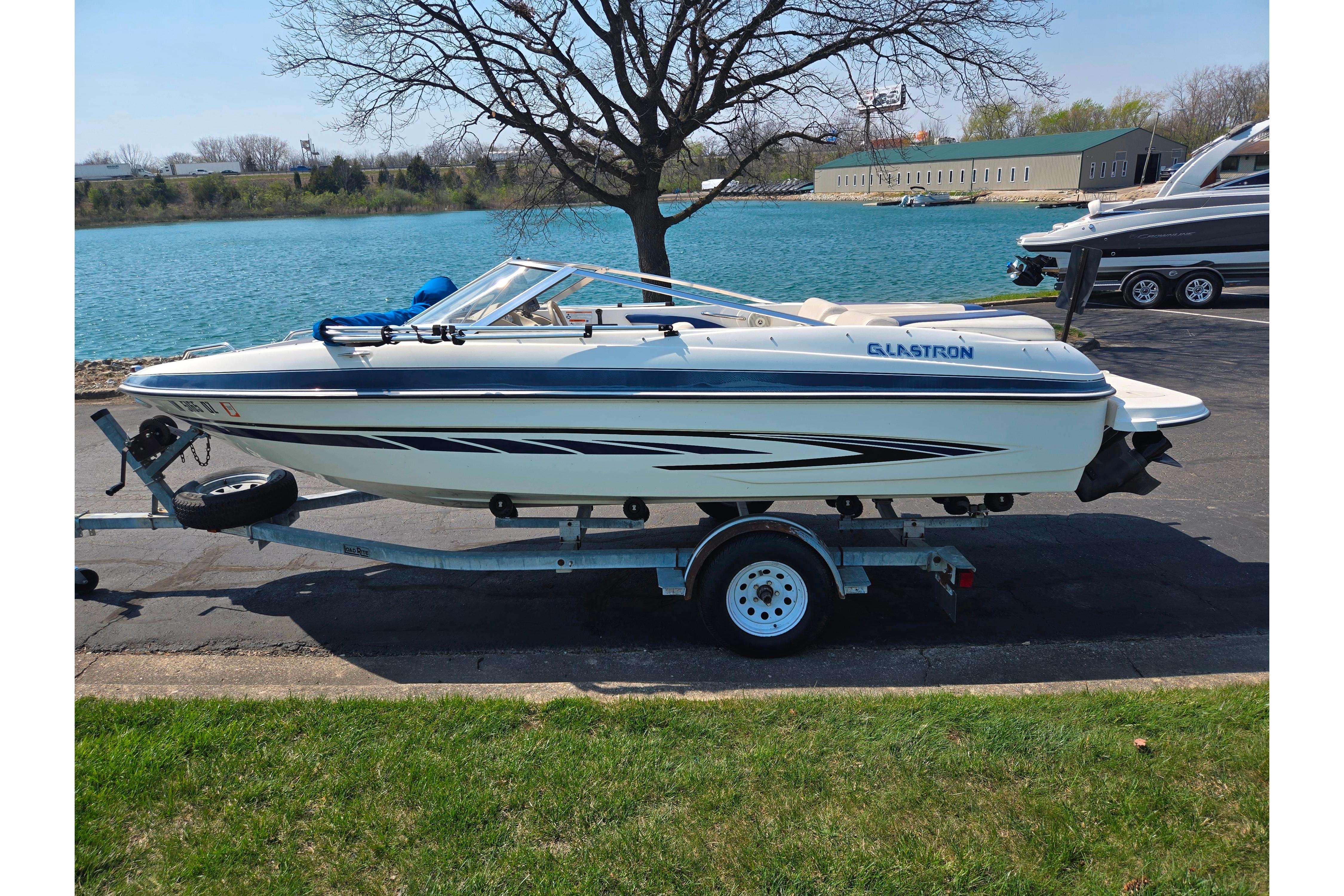 2007 Glastron GT 185 boat on trailer by a lake, sunny day.