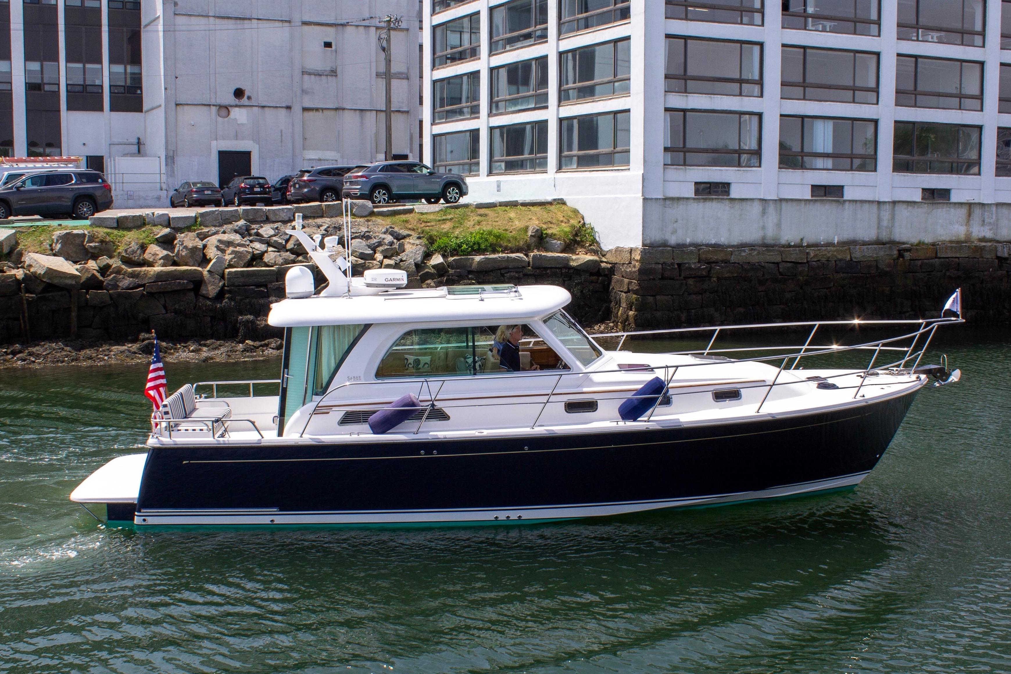 A Sabre 38 Salon Express boat cruising on the water near a building.