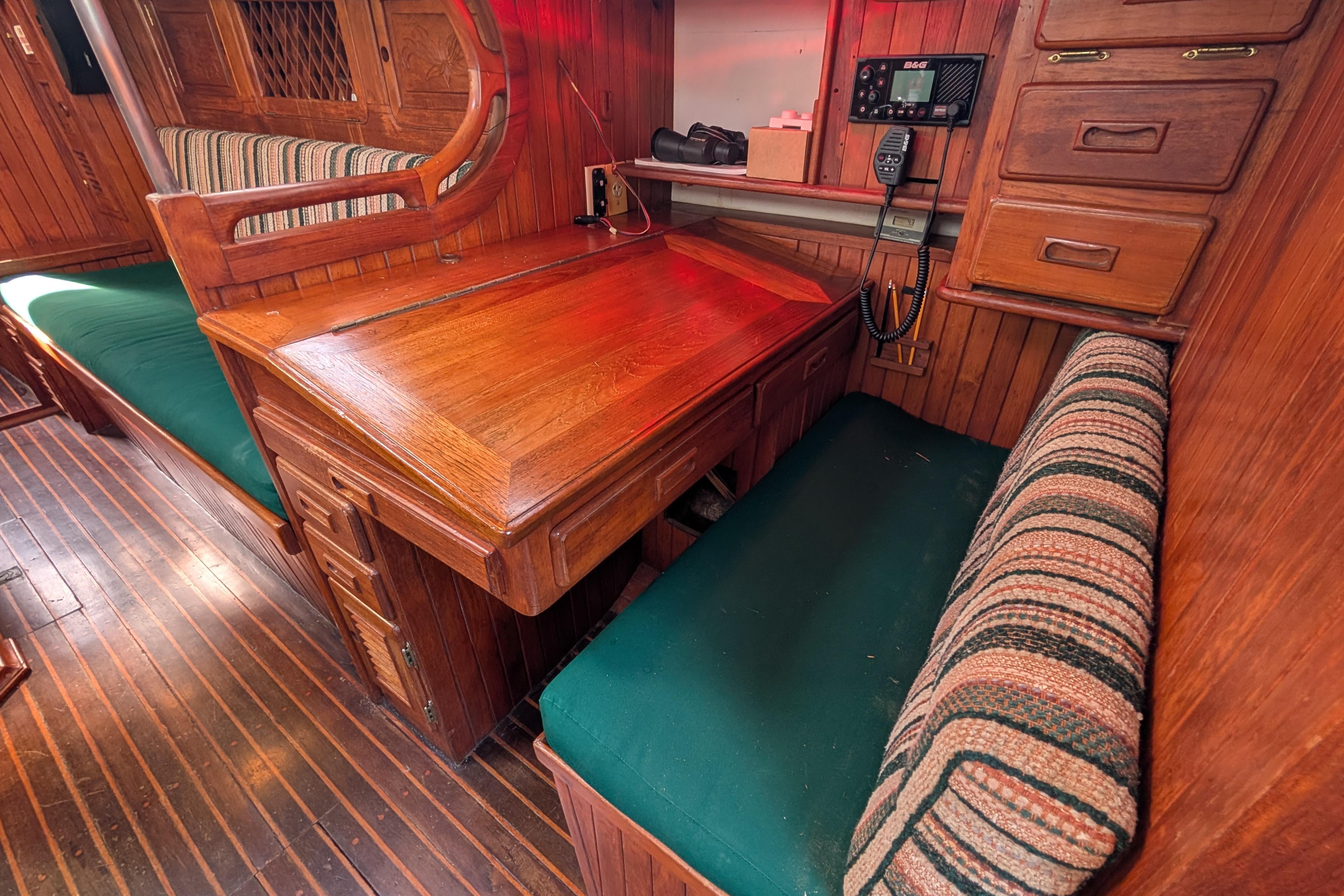 Interior of 1983 Robert Perry 41 sailboat with wooden desk and seating area.