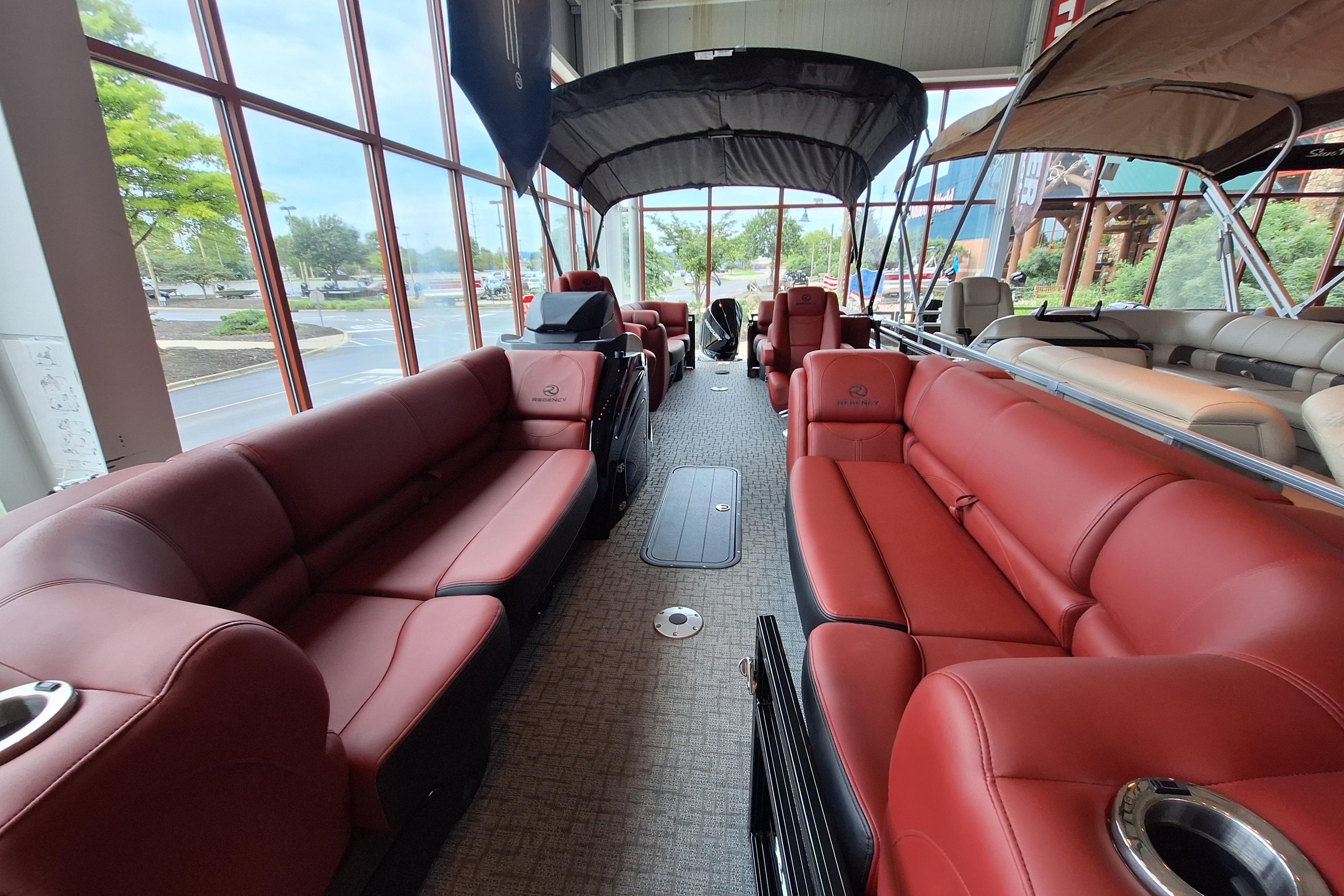 Luxurious interior of 2026 Regency 230 DL pontoon boat with red seating and canopy.