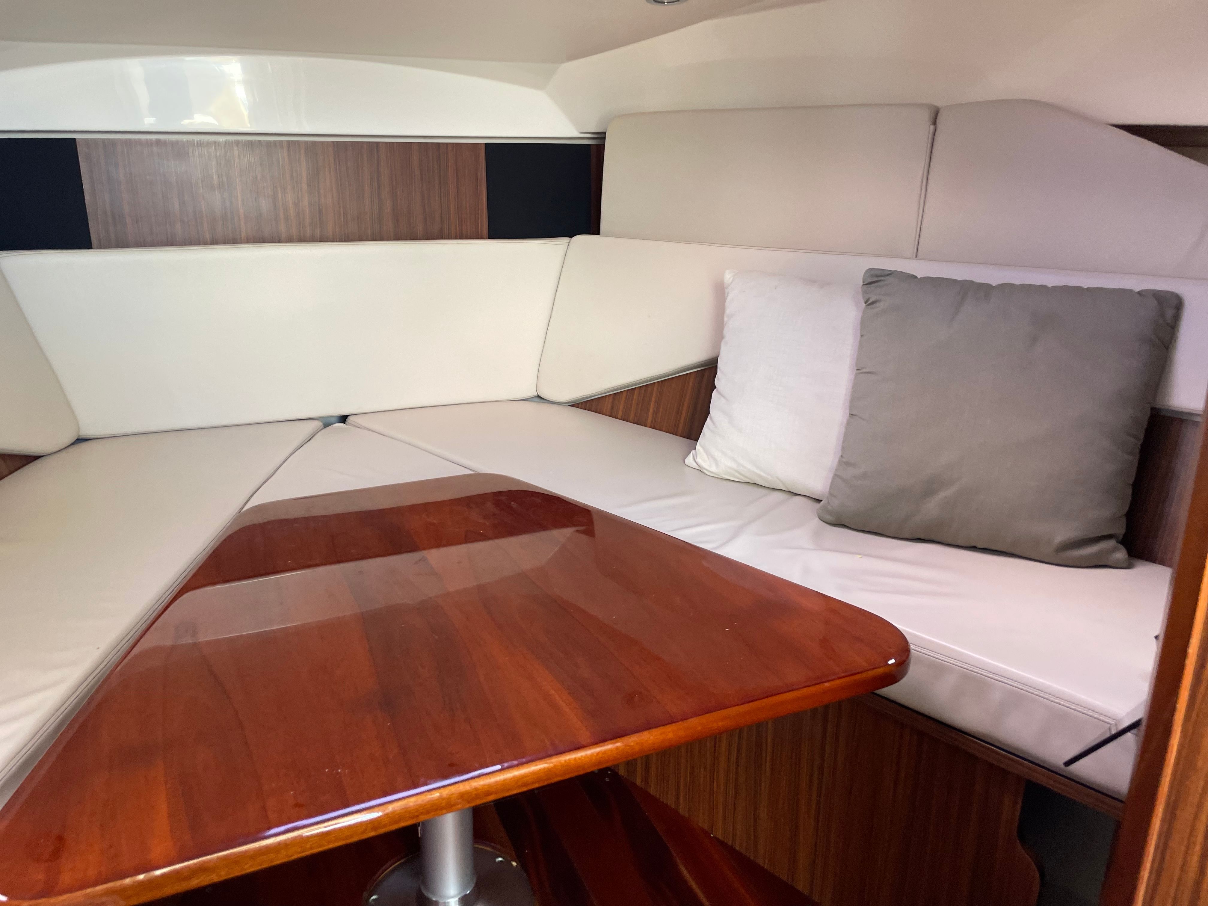 Interior of 2016 Pursuit OS 325 Offshore with wooden table and cushions.