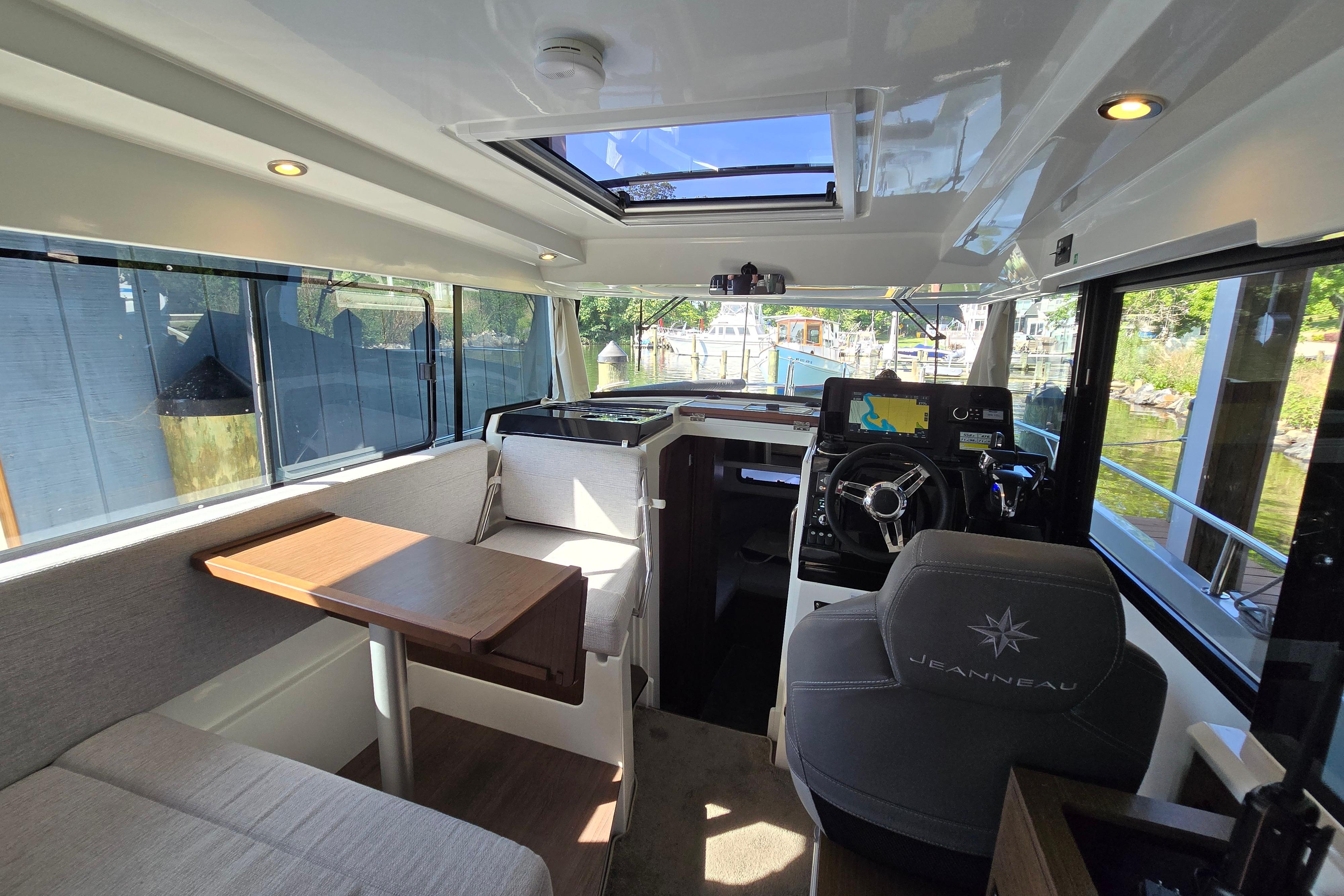 Interior of a Jeanneau NC Sport 895 with table, seating, and helm station.