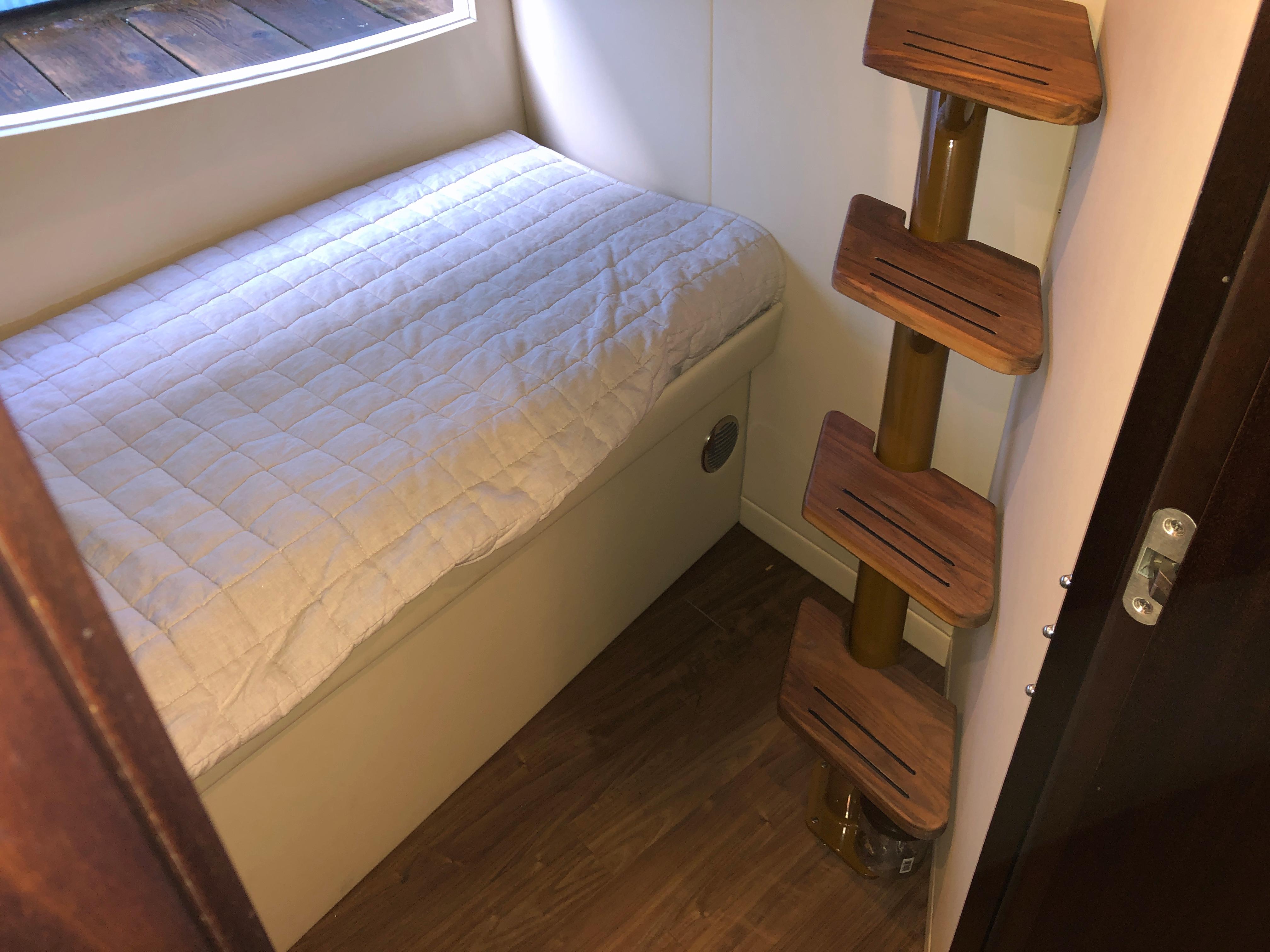 Cozy cabin interior of 2017 Regal 53 Sport Coupe with bed and wooden steps.
