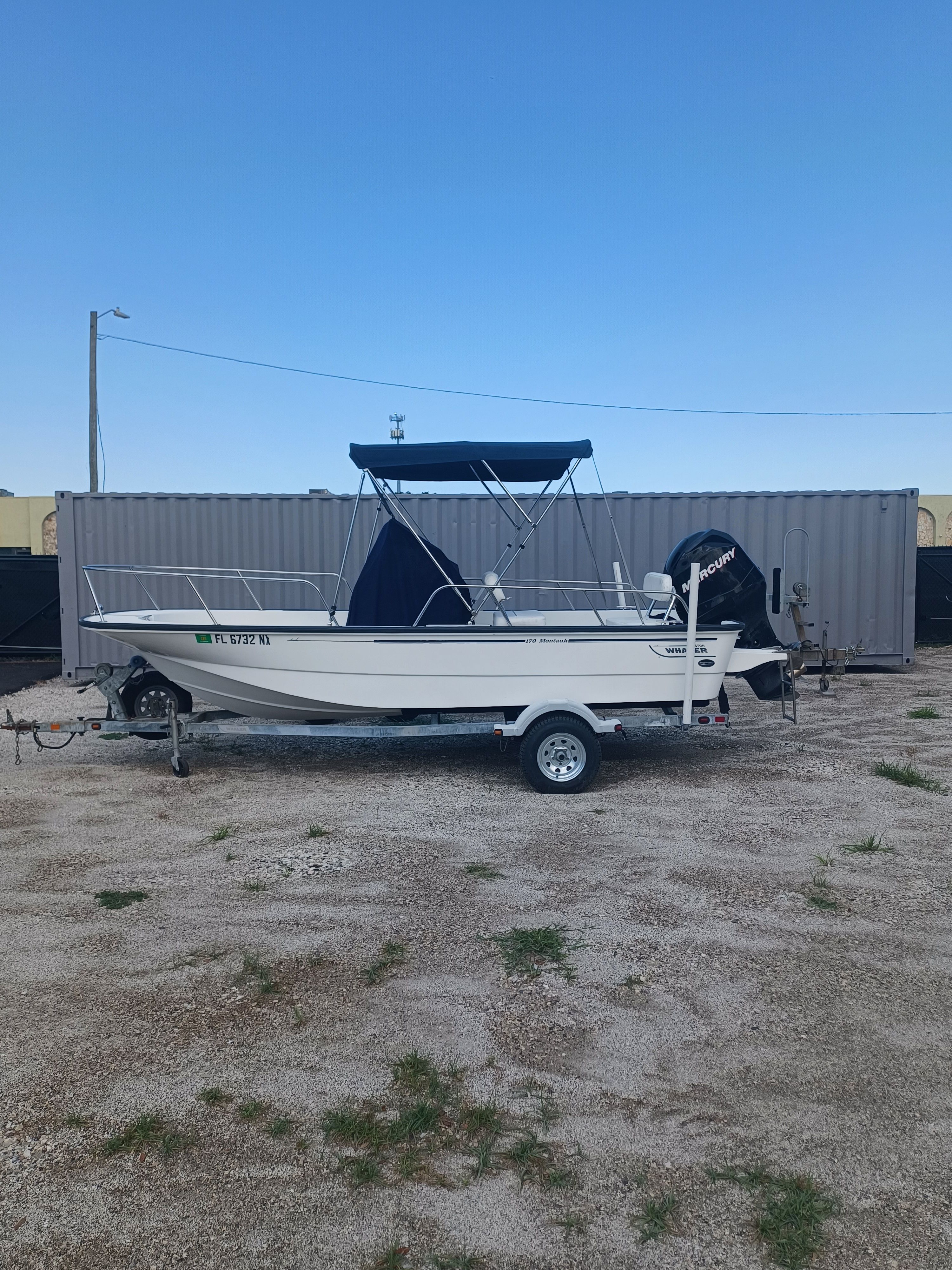 Boston Whaler 170 Montauk 2008 on a trailer, with blue cover and outboard motor.
