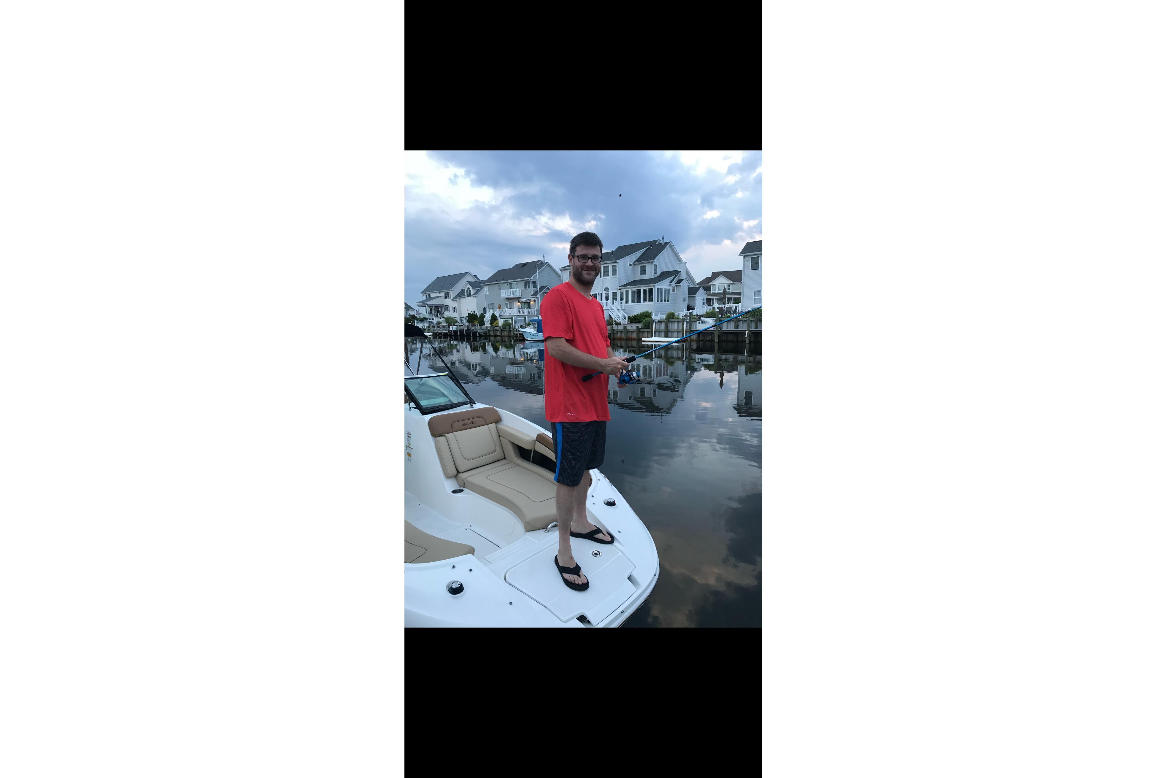 Man fishing on a 2014 Sea Ray 260 Sundeck boat near waterfront homes.