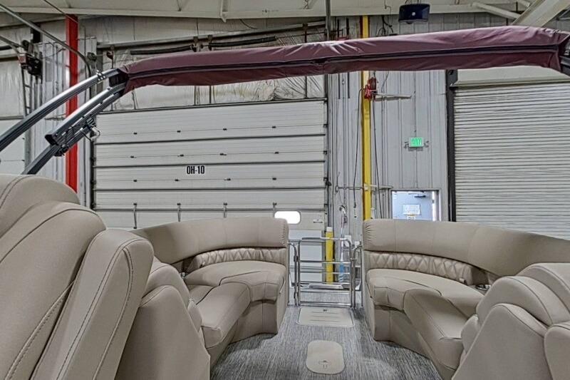 2026 Bennington 24 LXS Quadbench interior with plush seating in a spacious boat showroom.