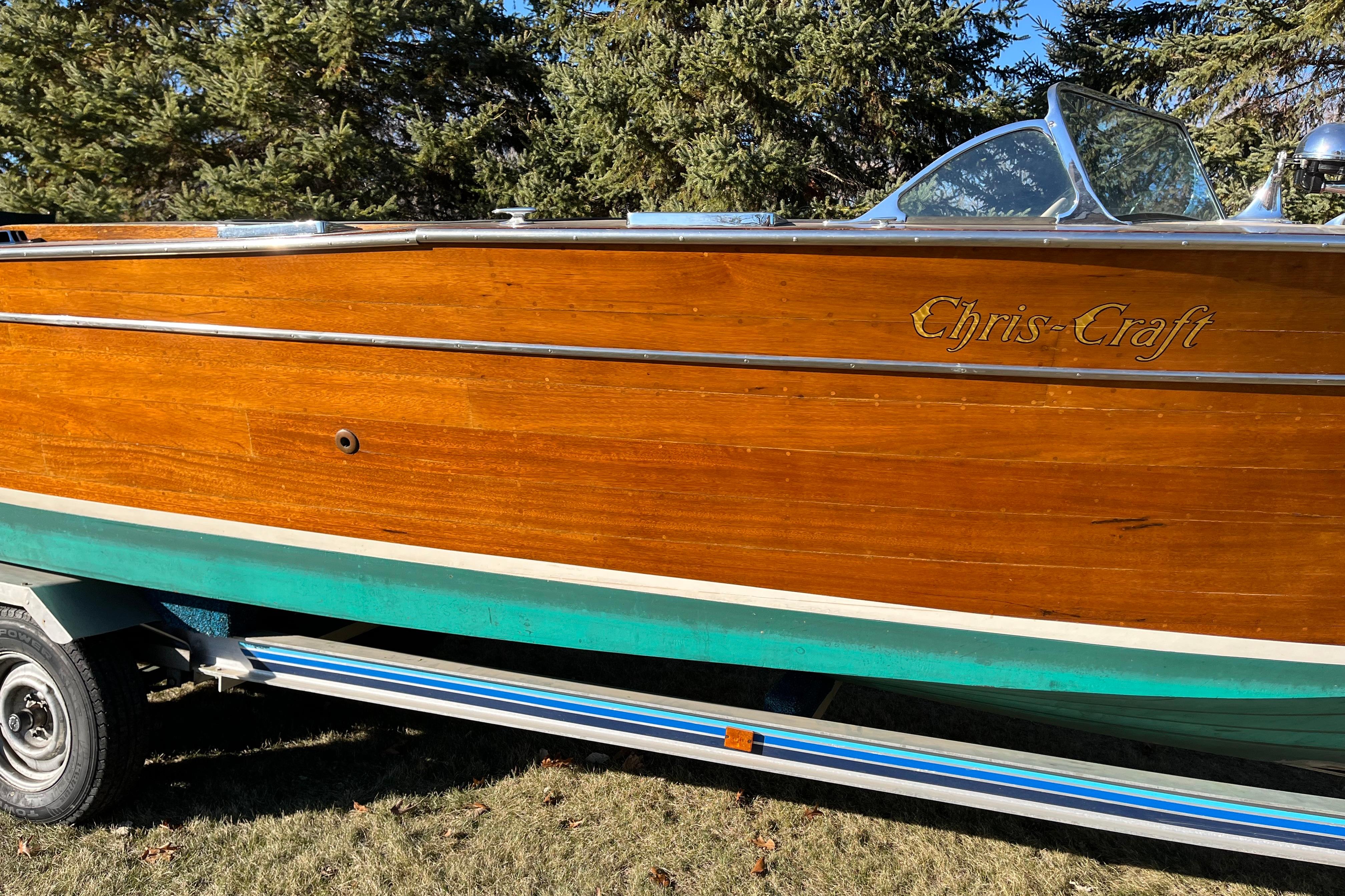 1938 Chris-Craft 28 Sportsman wooden boat on trailer, surrounded by trees.