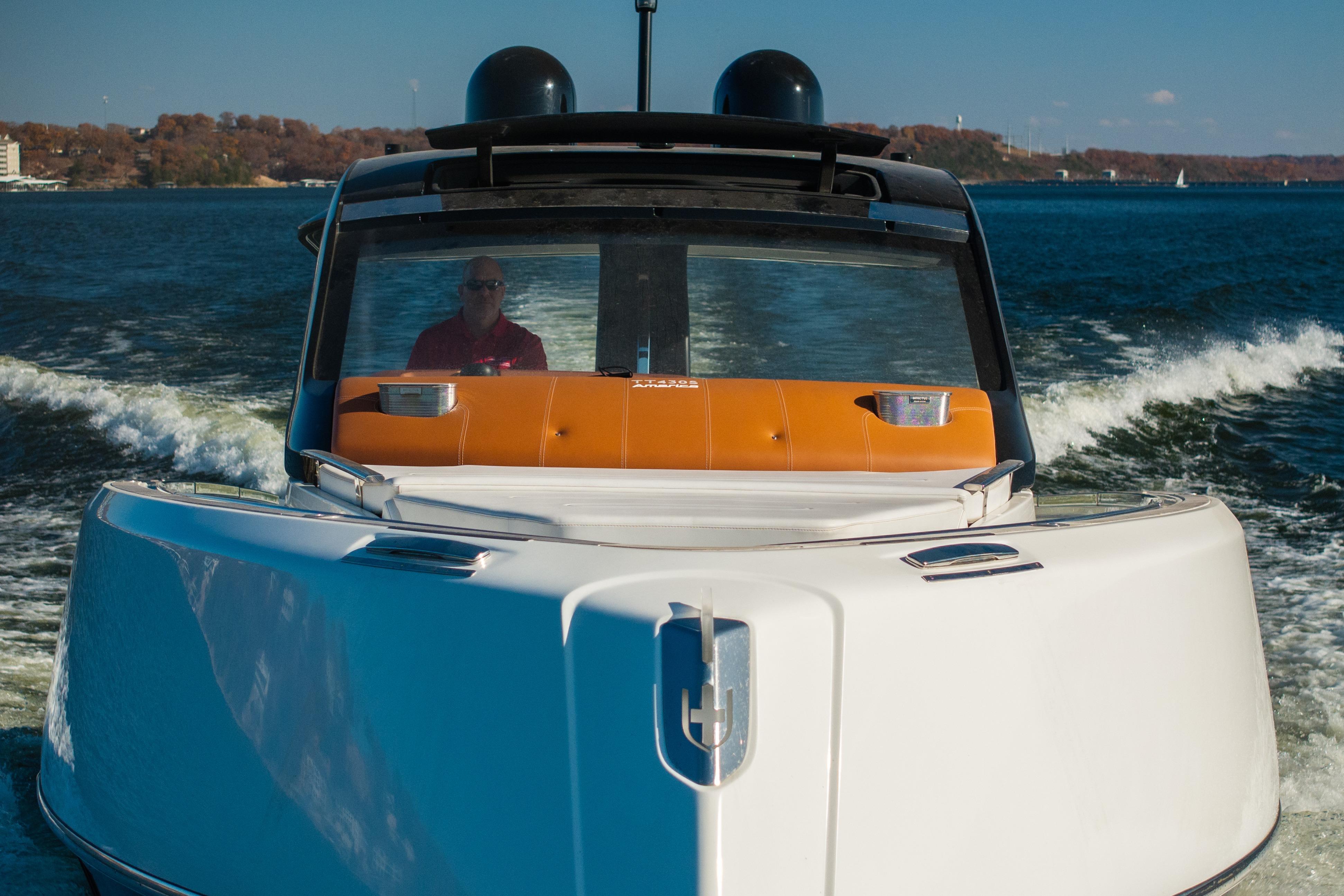 2025 Invictus TT430 yacht cruising on a sunny day, with a person at the helm.