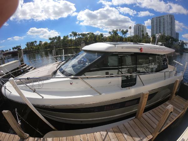 2017 Jeanneau NC 11 boat docked at a marina with cityscape background.