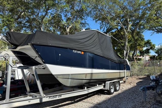 2003 World Cat 270 EC boat on trailer, covered, parked outdoors.