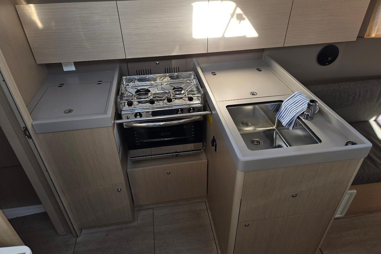 Modern kitchen in 2023 Beneteau Oceanis 38.1 yacht with stove and sink.