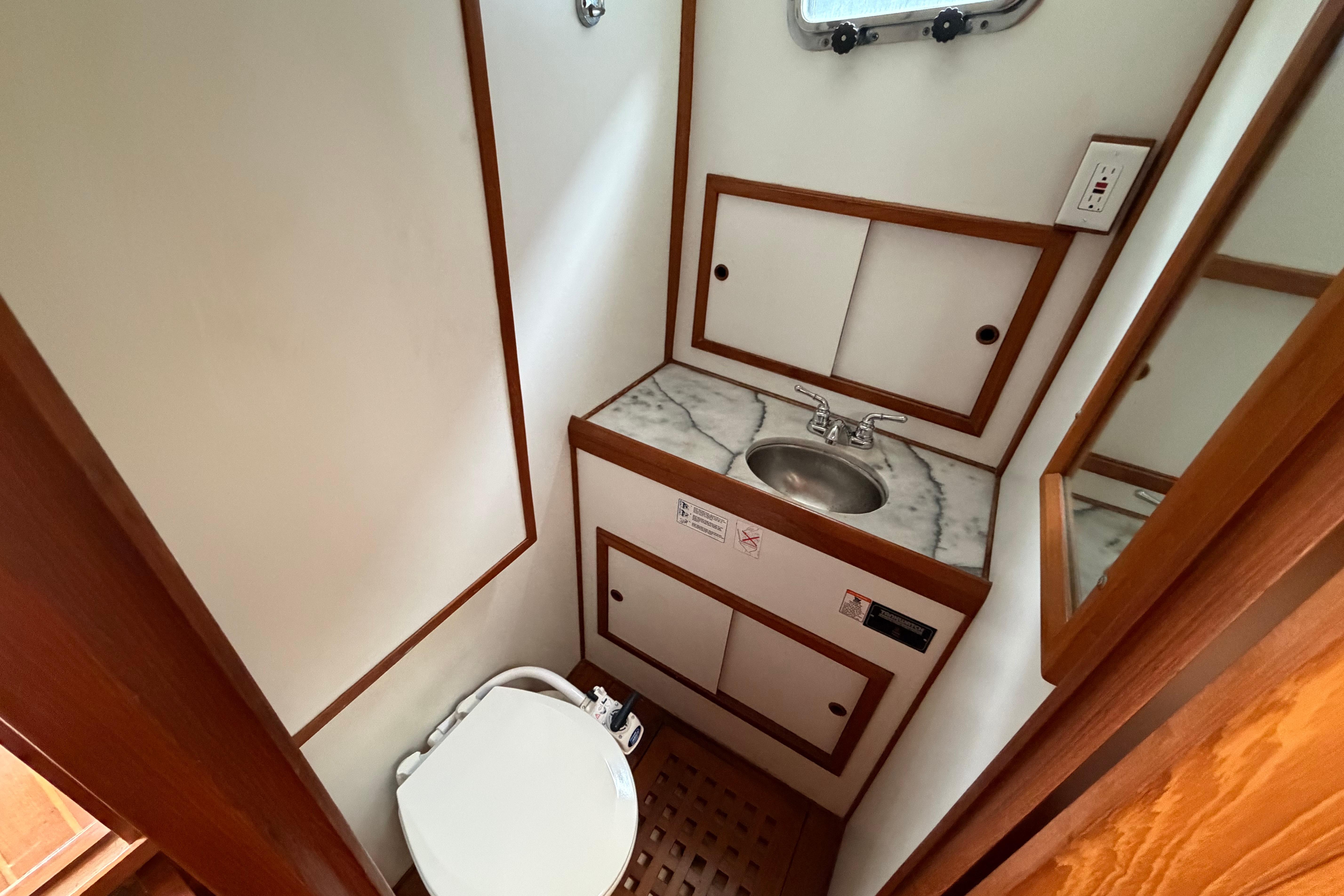 Compact bathroom in a 1988 Monk 36 boat, featuring a sink and toilet.