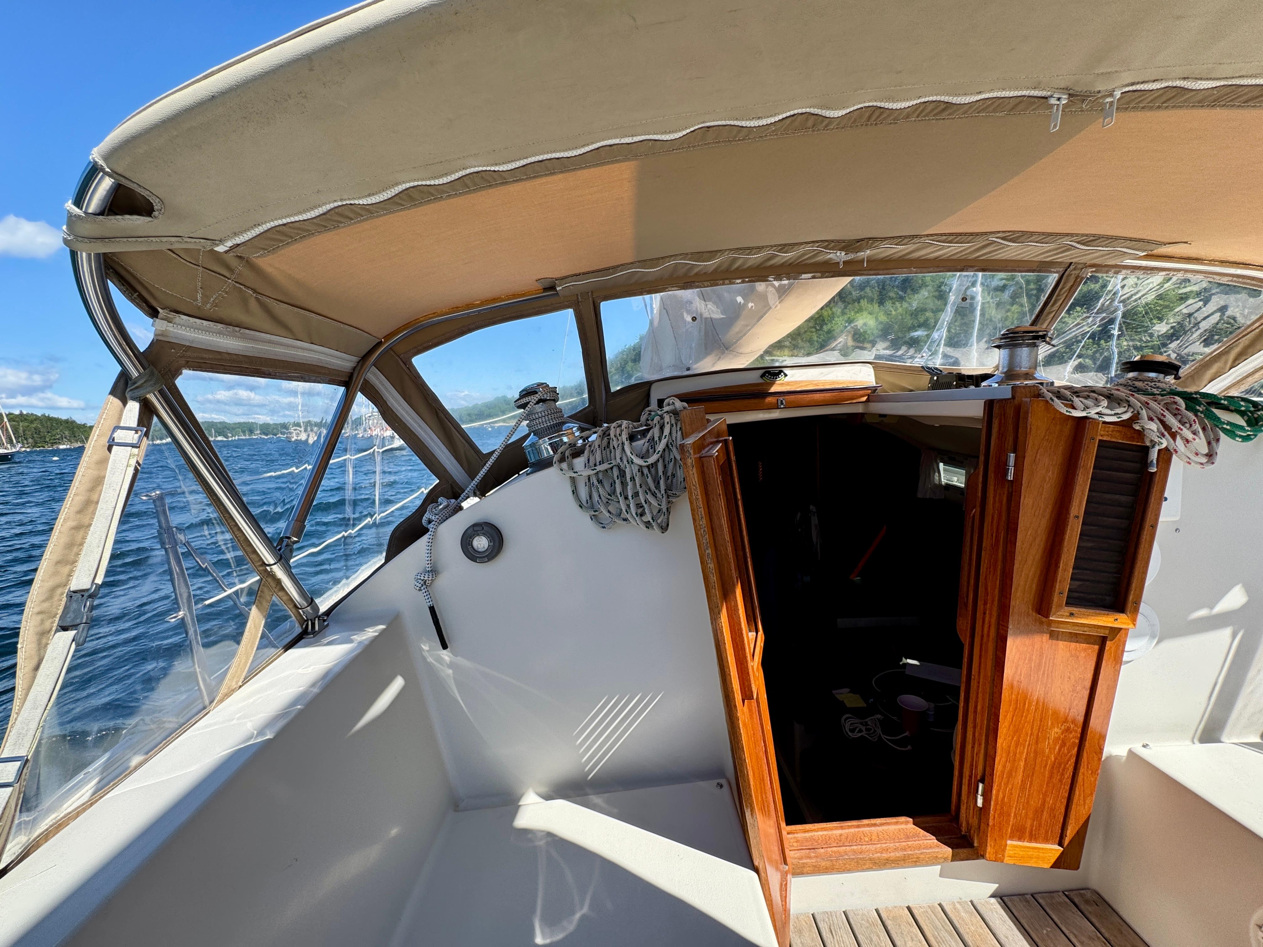 1989 Nonsuch 30 Ultra sailboat cockpit with open cabin door, under sunny skies.